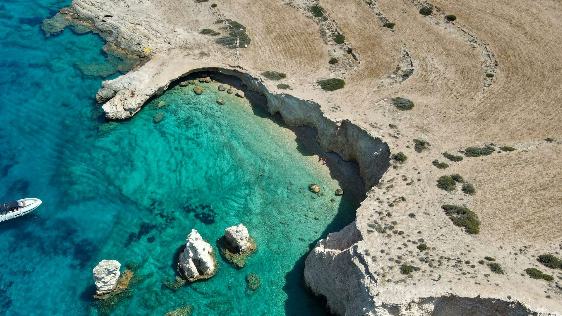 An aerial view of a beach with boats in the water