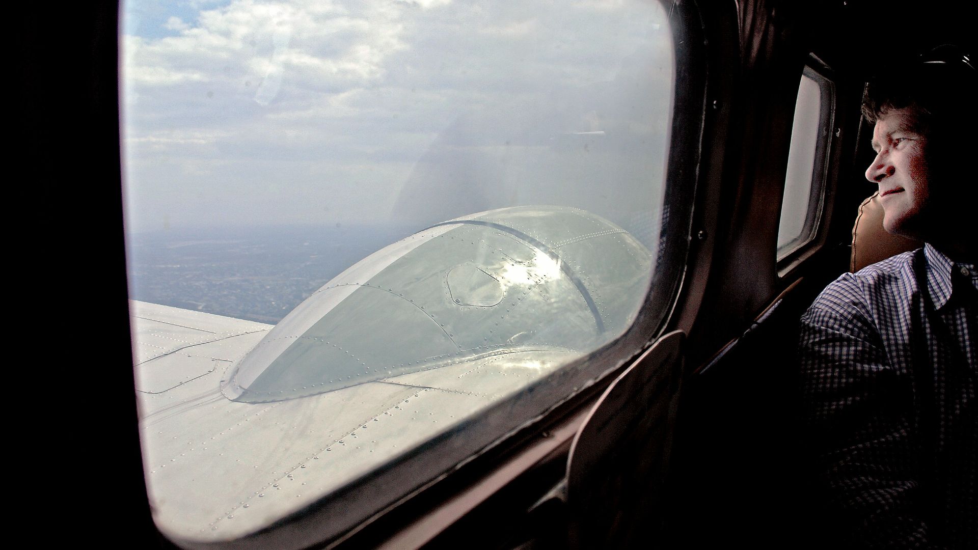 Man looking out airplane window at clouds