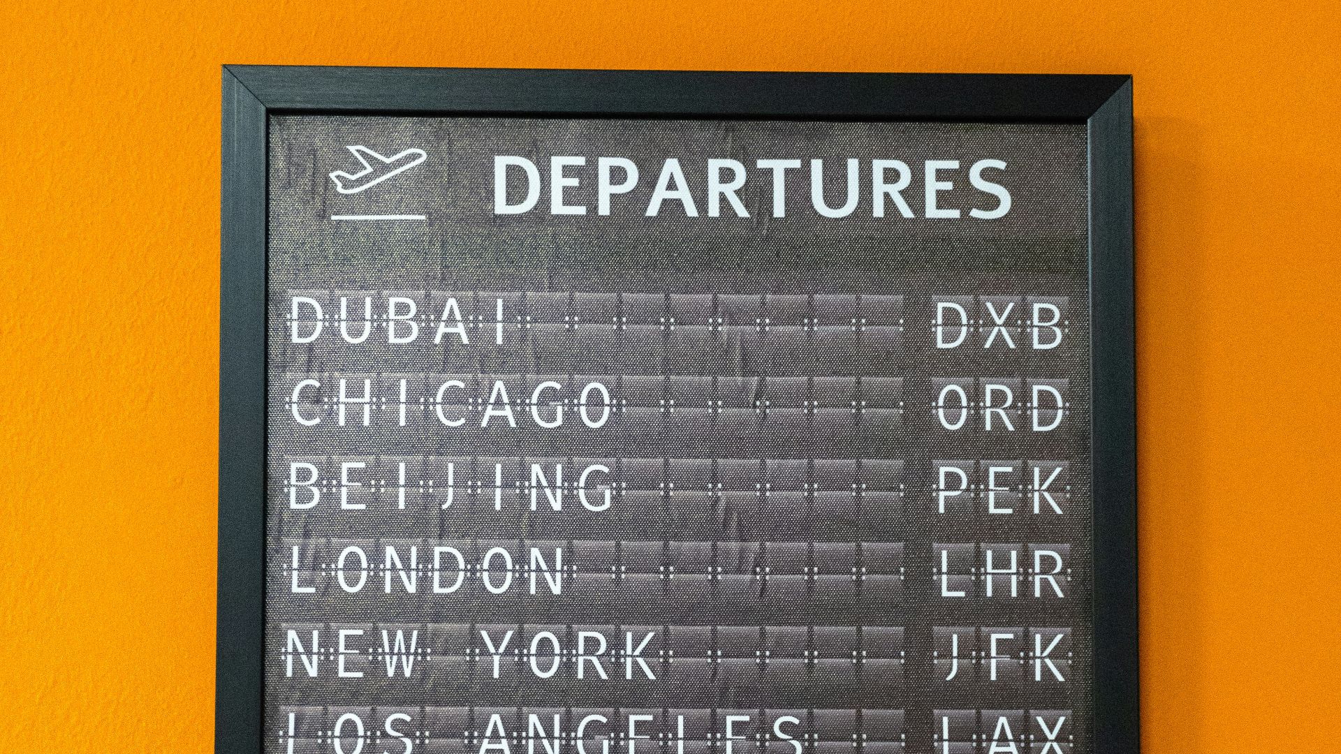 An airport departure board displays flight information.