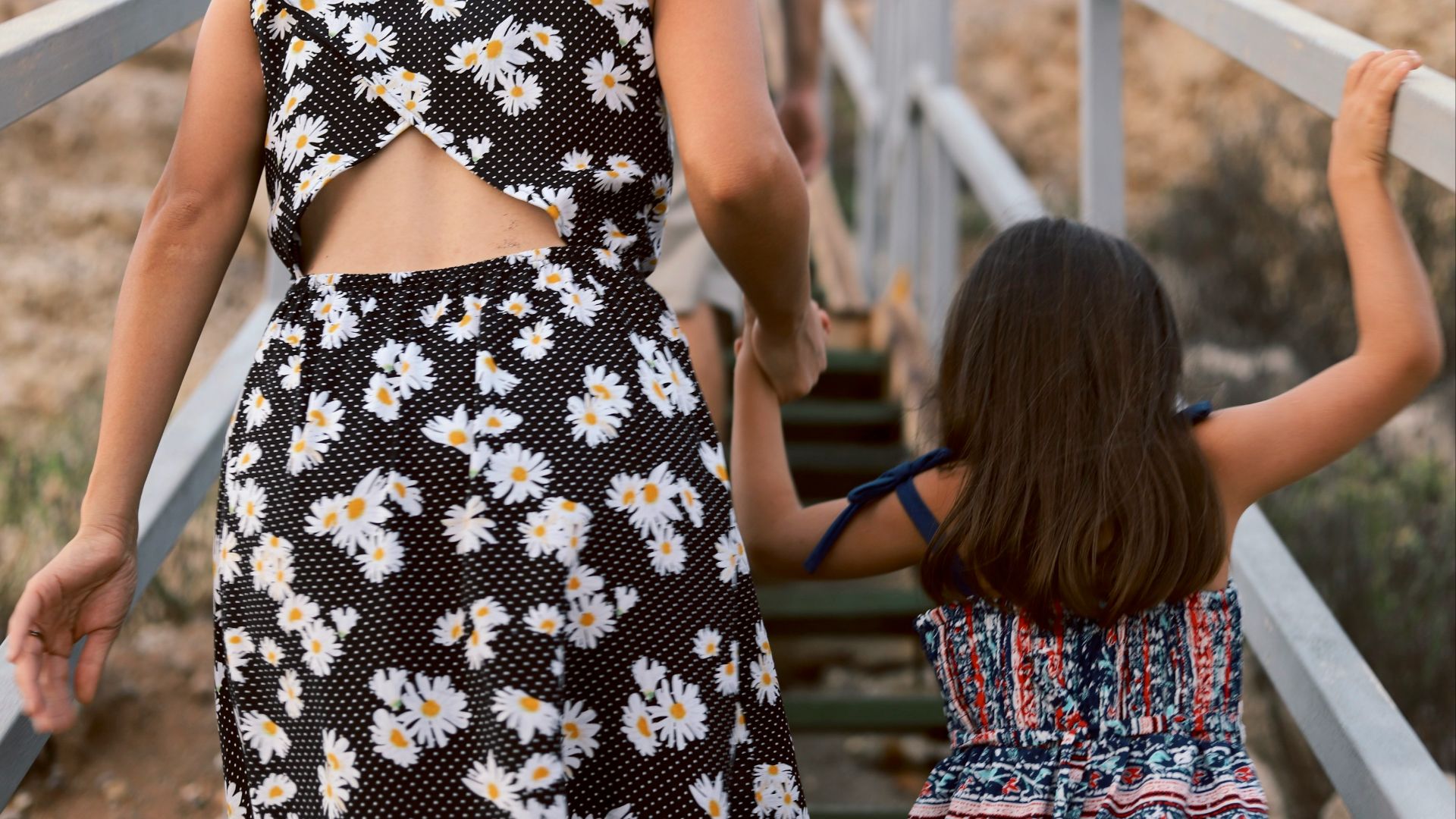 woman and girl walking on wooden stair during daytime
