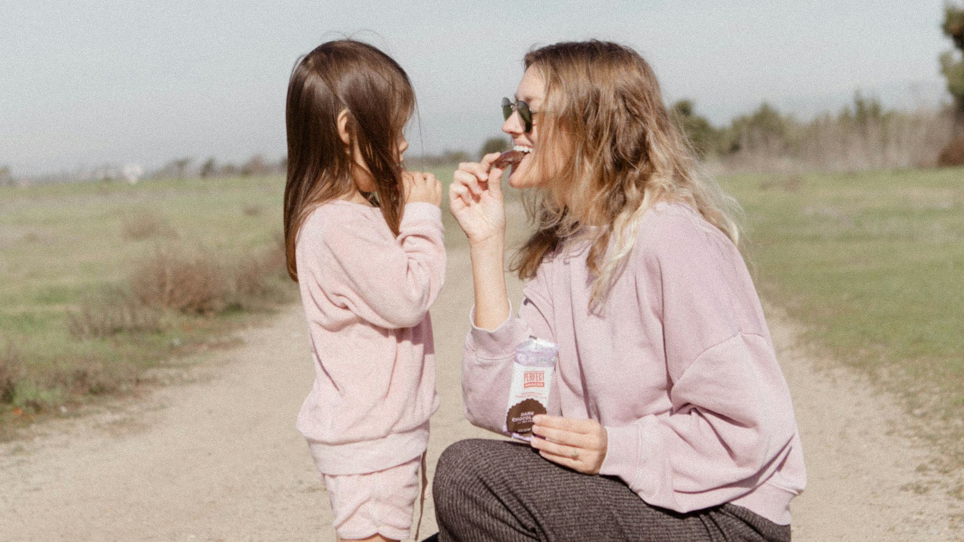 2 women sitting on brown sand during daytime