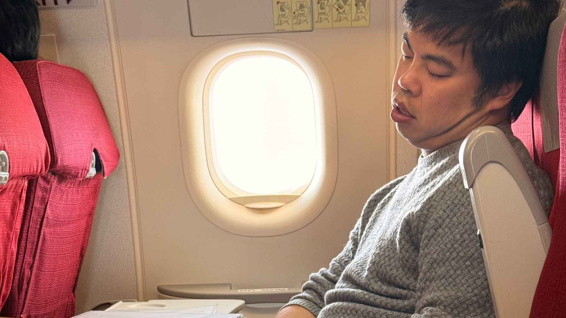 Man sleeping on airplane with laptop on tray