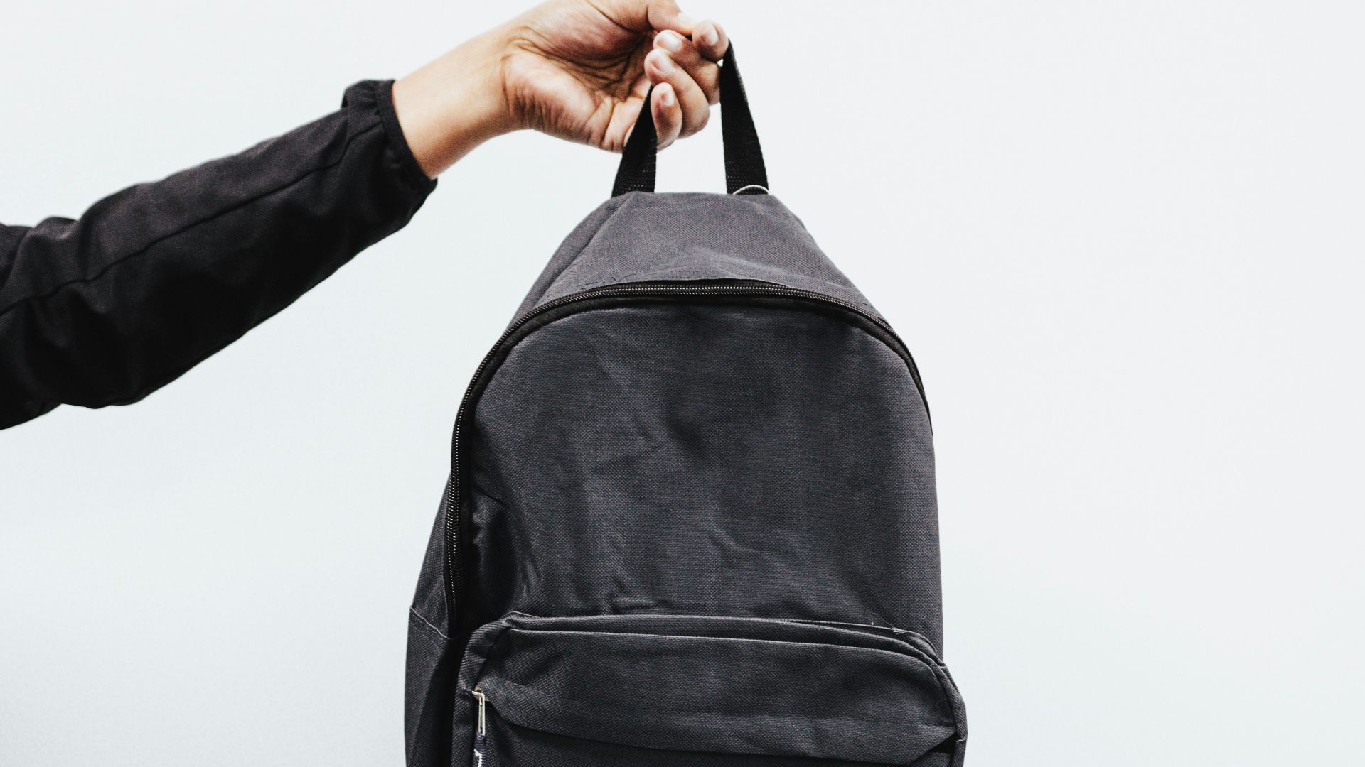 person in black jacket holding black backpack