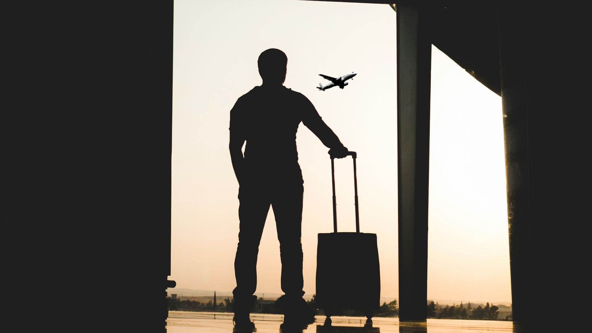 silhouette of man holding luggage inside airport
