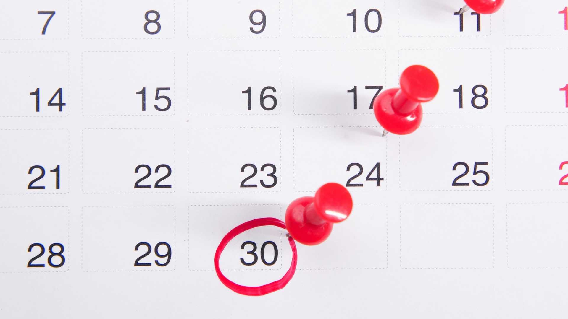 a calendar with red push buttons pinned to it