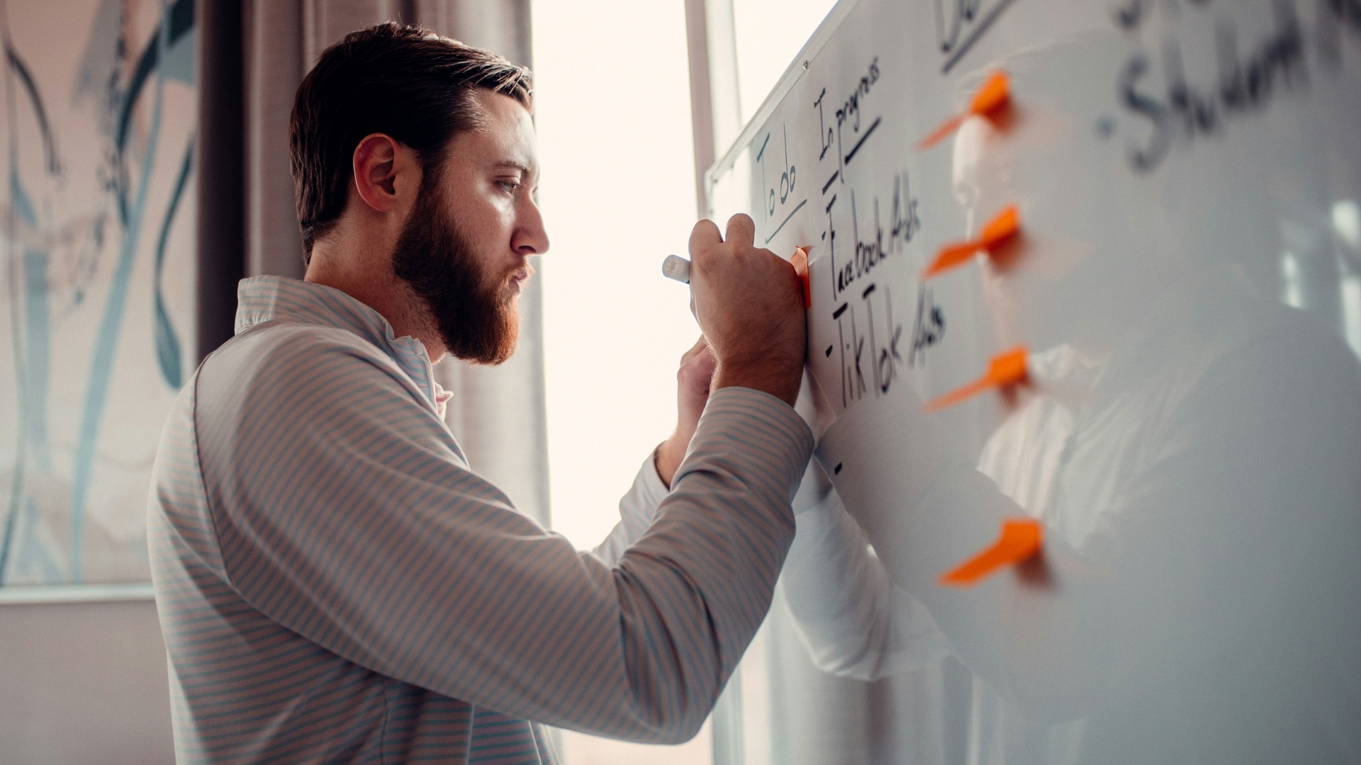 a man writing on a white board with orange markers
