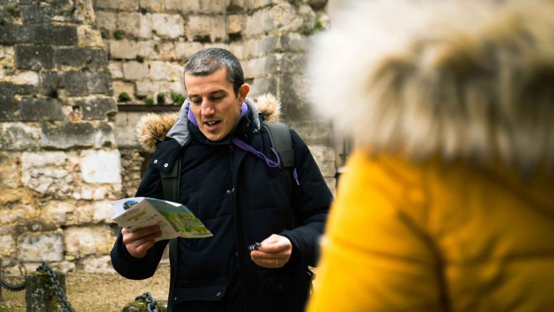 a man standing in front of a stone wall