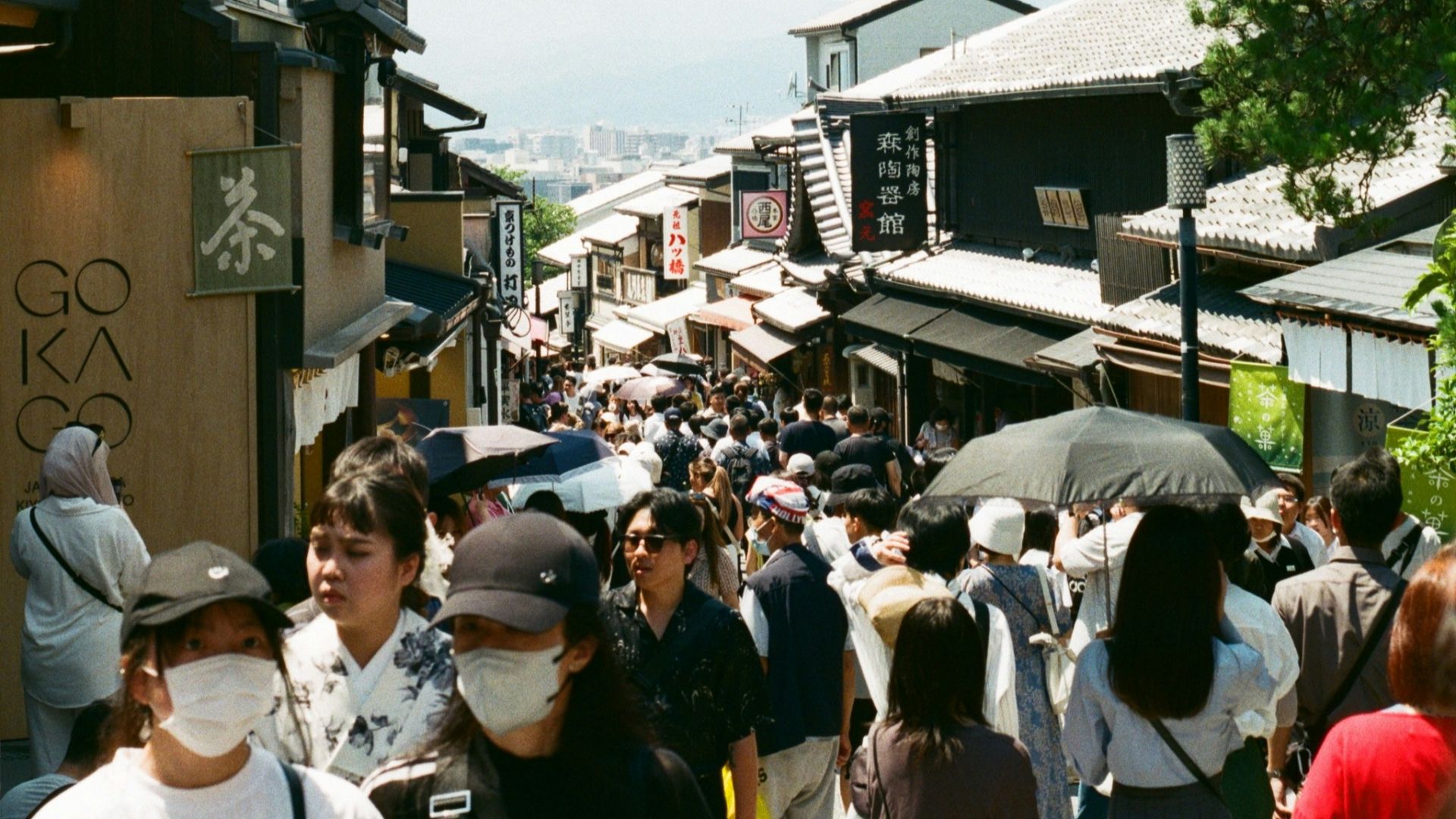 A crowd of people walking down a street next to tall buildings