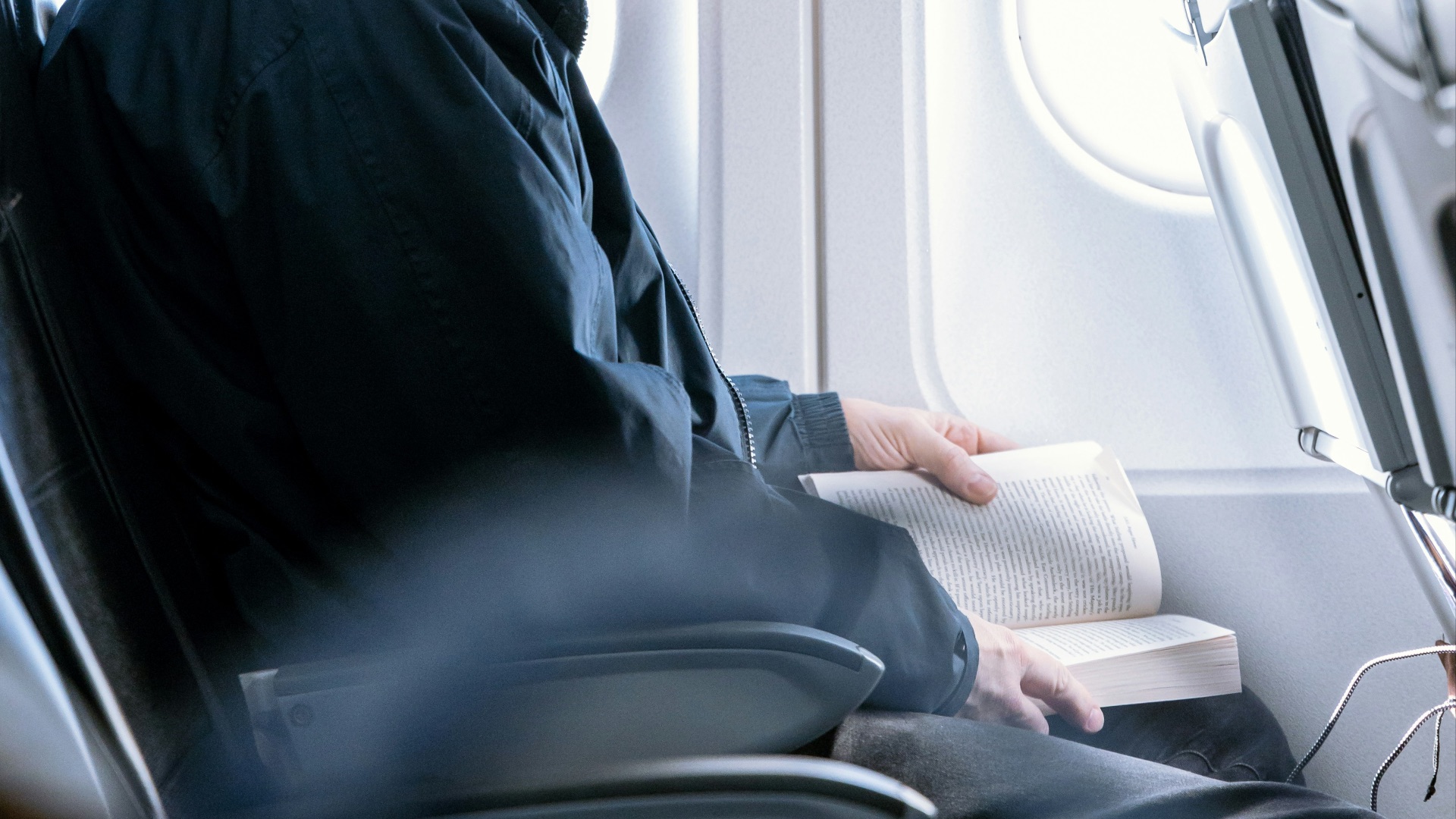 a man reading a book on an airplane
