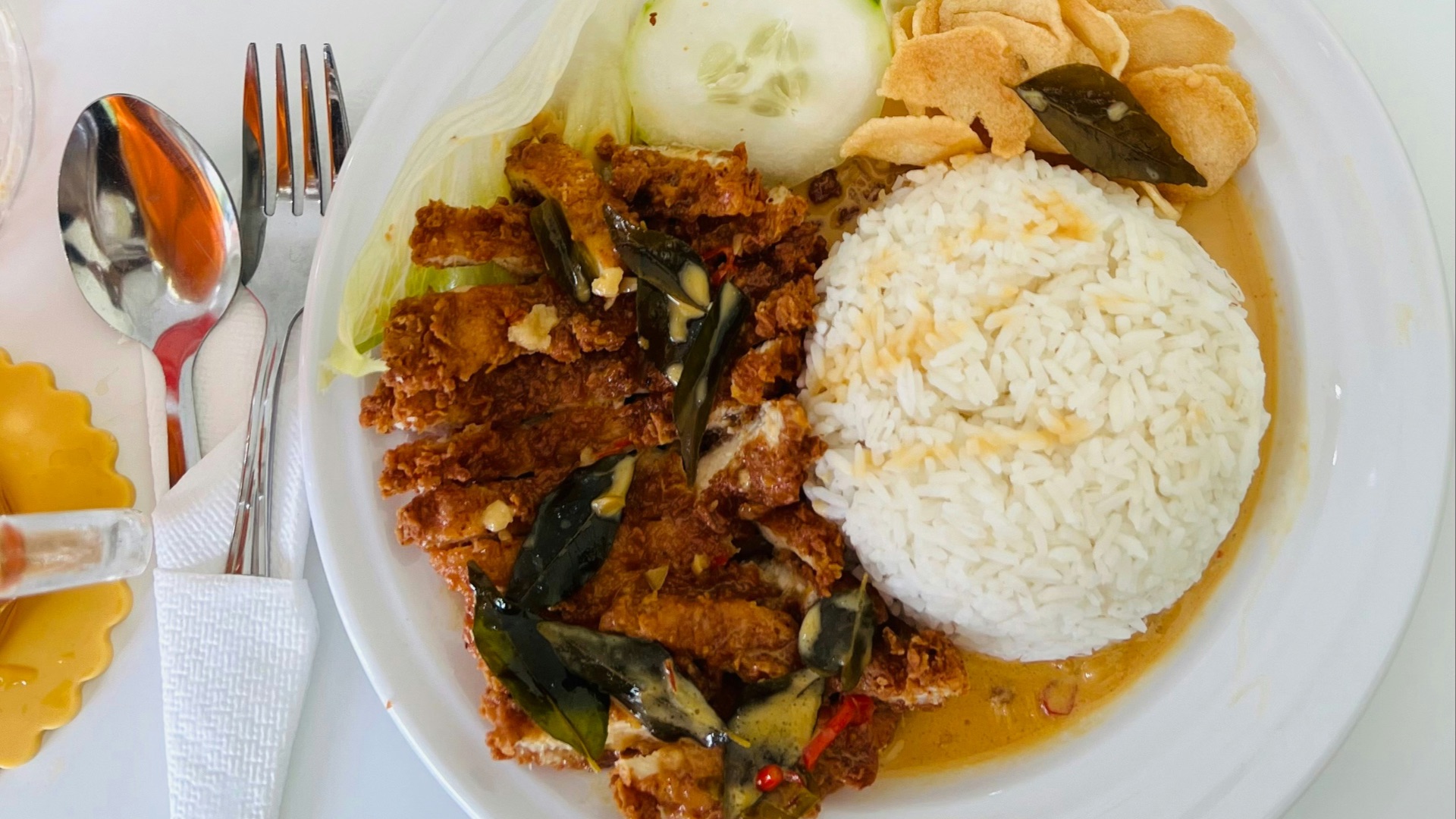 A white plate topped with meat and rice