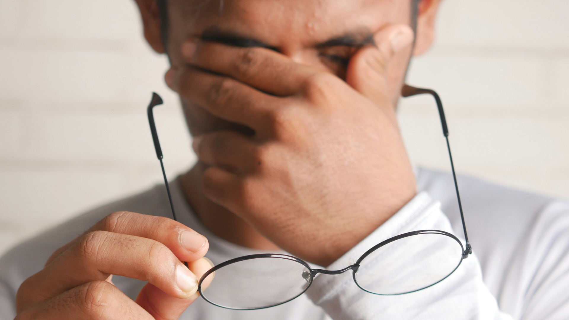 a man holding a pair of glasses up to his face