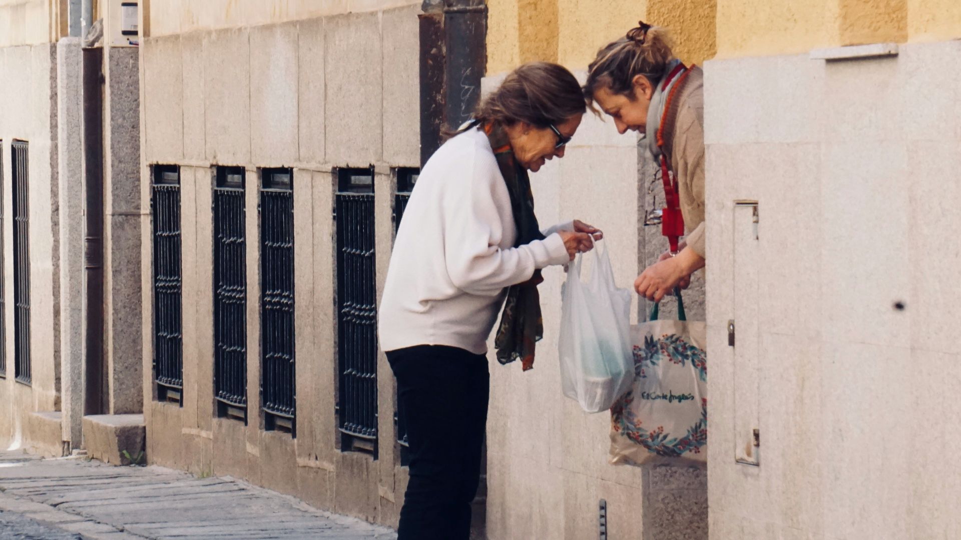 woman in white long sleeve shirt and black pants standing on sidewalk during daytime