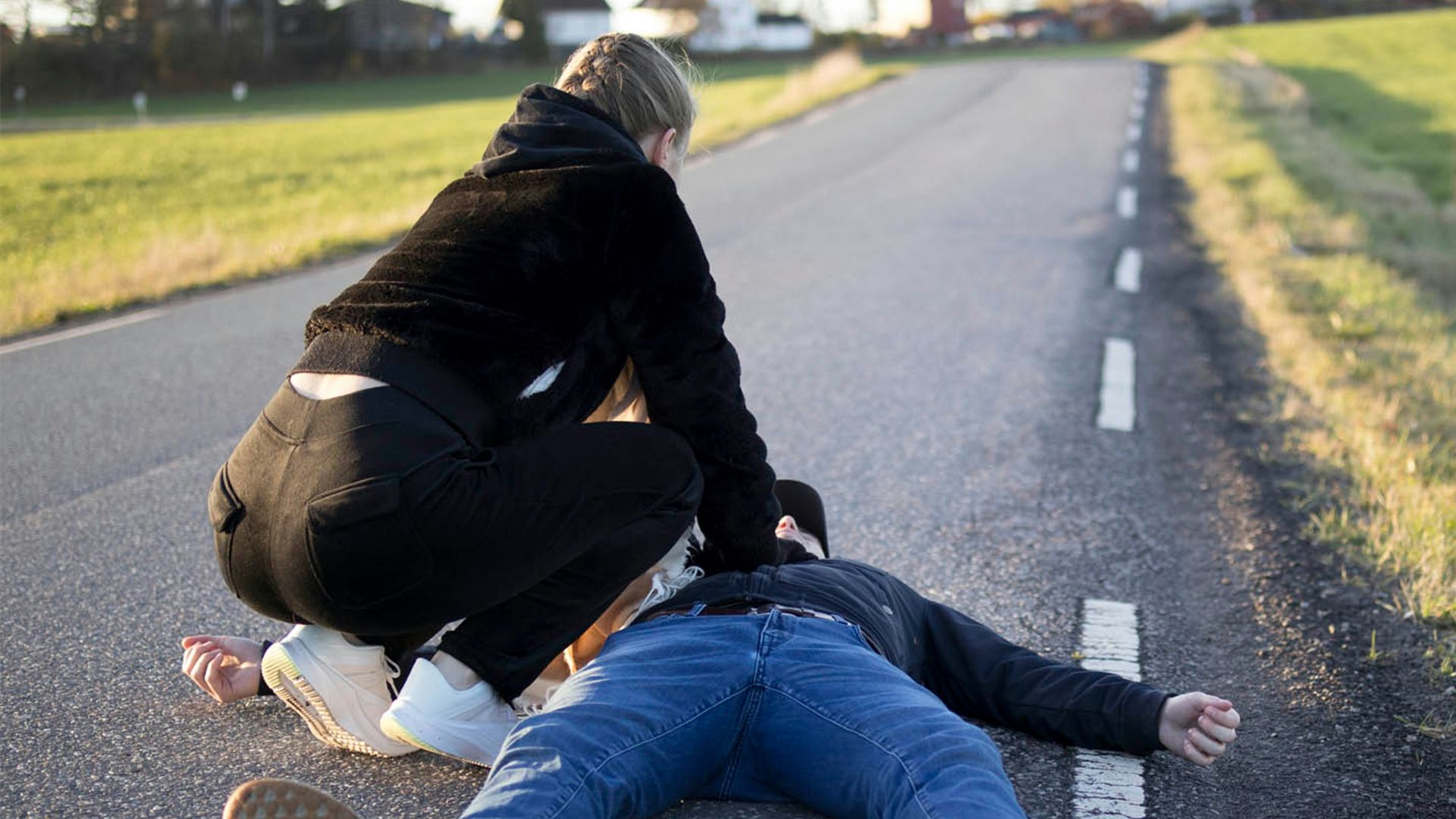 a man kneeling on the side of a road with another man kneeling on the ground