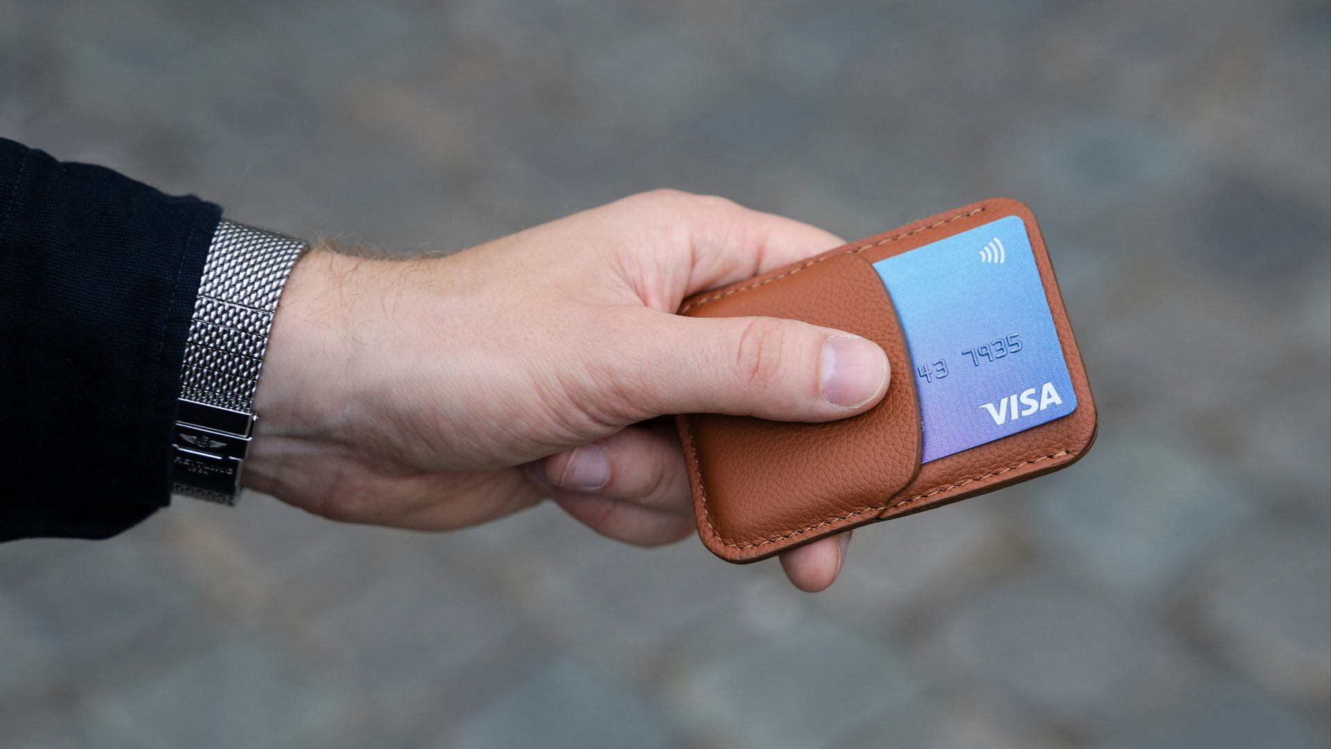 a hand holding a wallet with a credit card in it