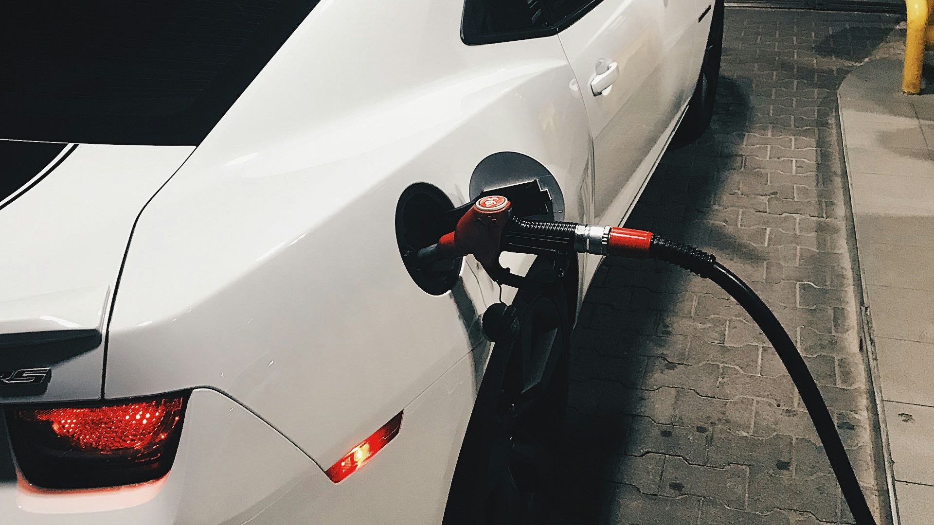 fueling white coupe at night