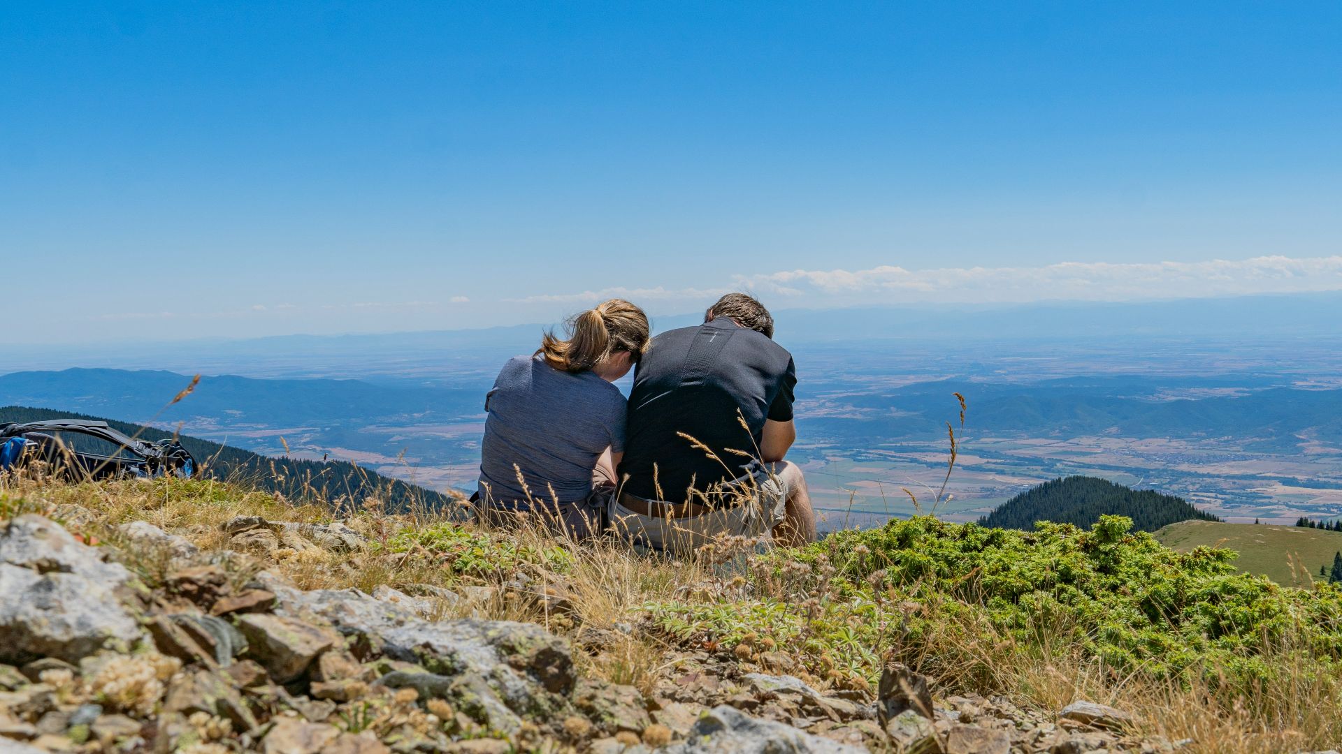 a couple of people sitting on top of a hill