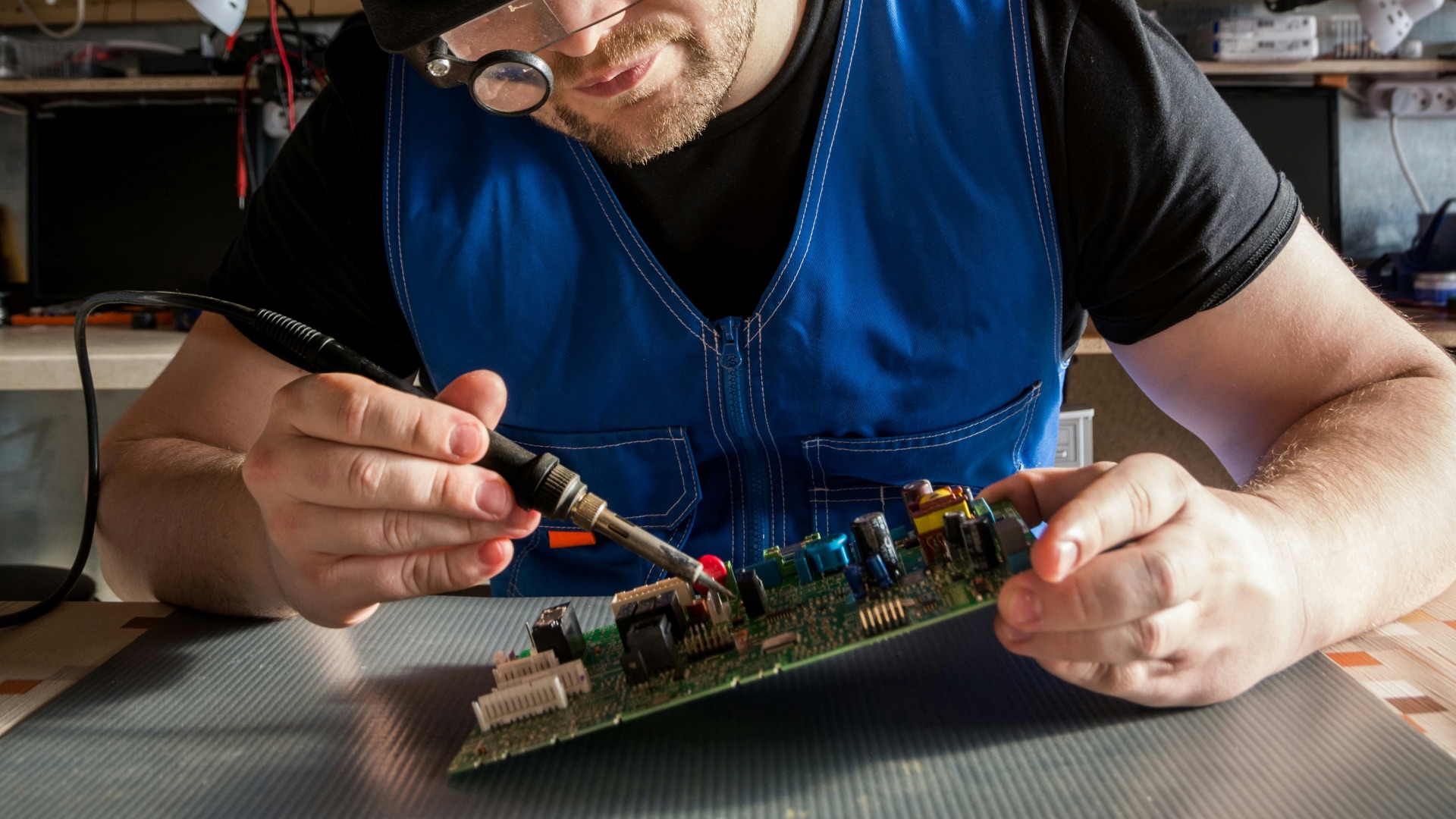 a man wearing a blindfold working on a circuit board