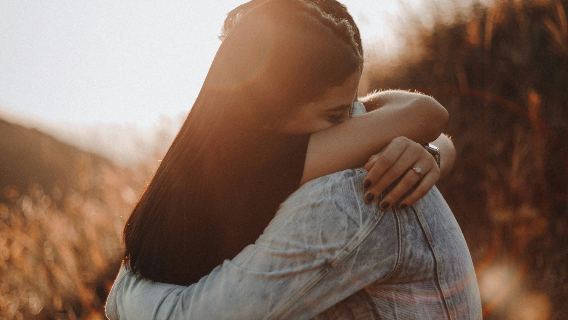 woman in black long sleeve shirt and blue denim jeans covering her face with her hand
