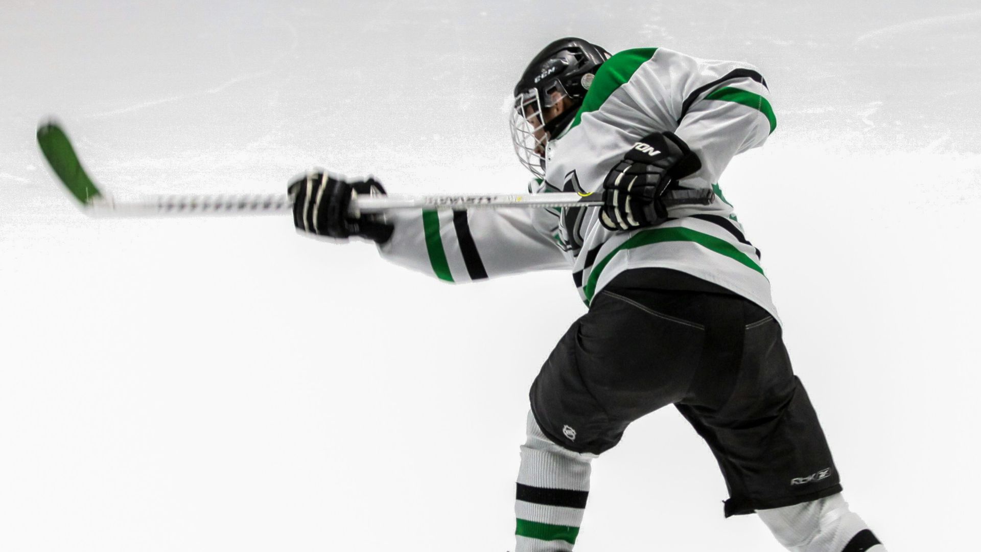 man wearing green and white ice hockey jersey while playing