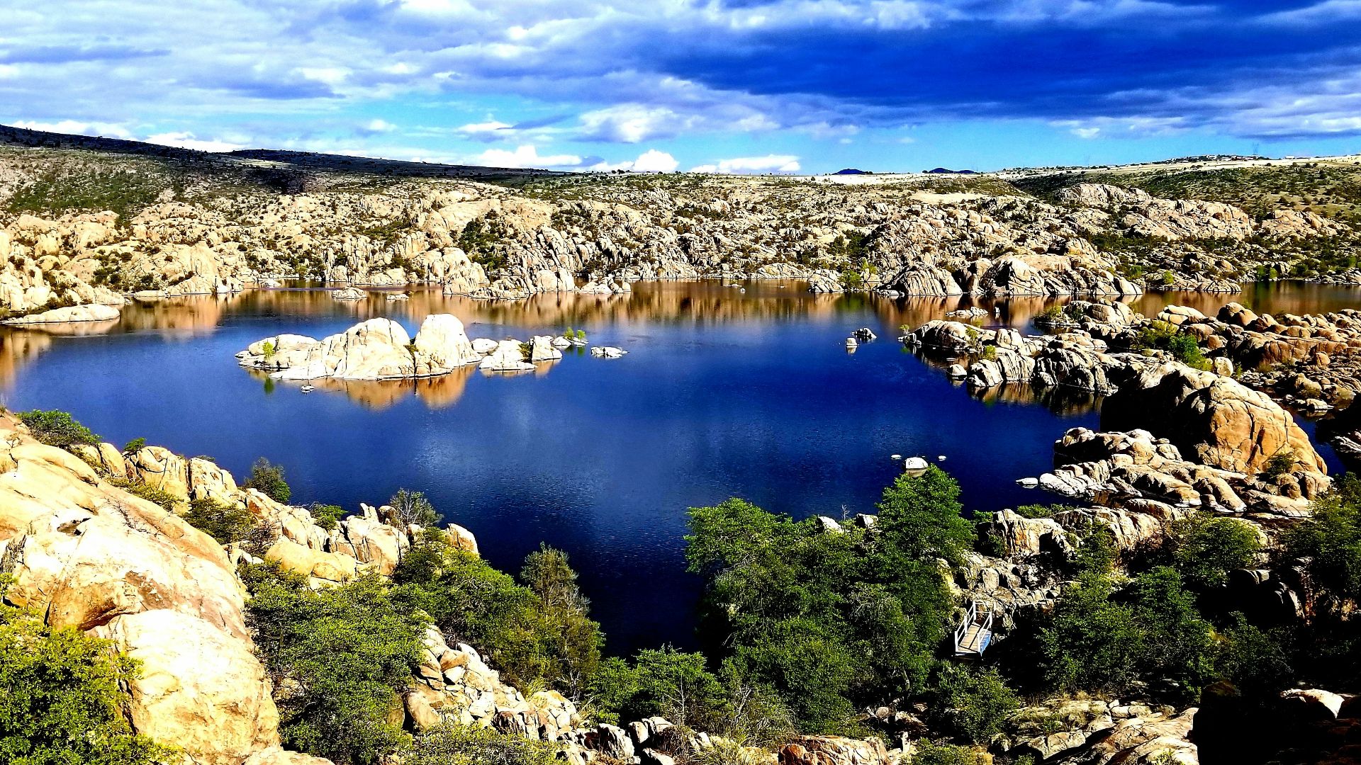 blue lake surrounded by brown rocks under blue sky during daytime