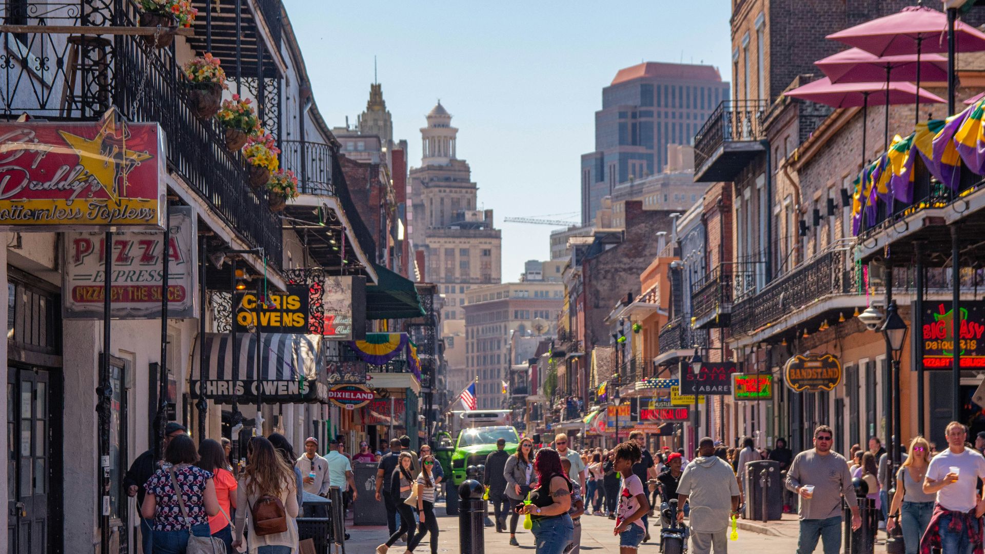 a group of people walking down a street next to tall buildings