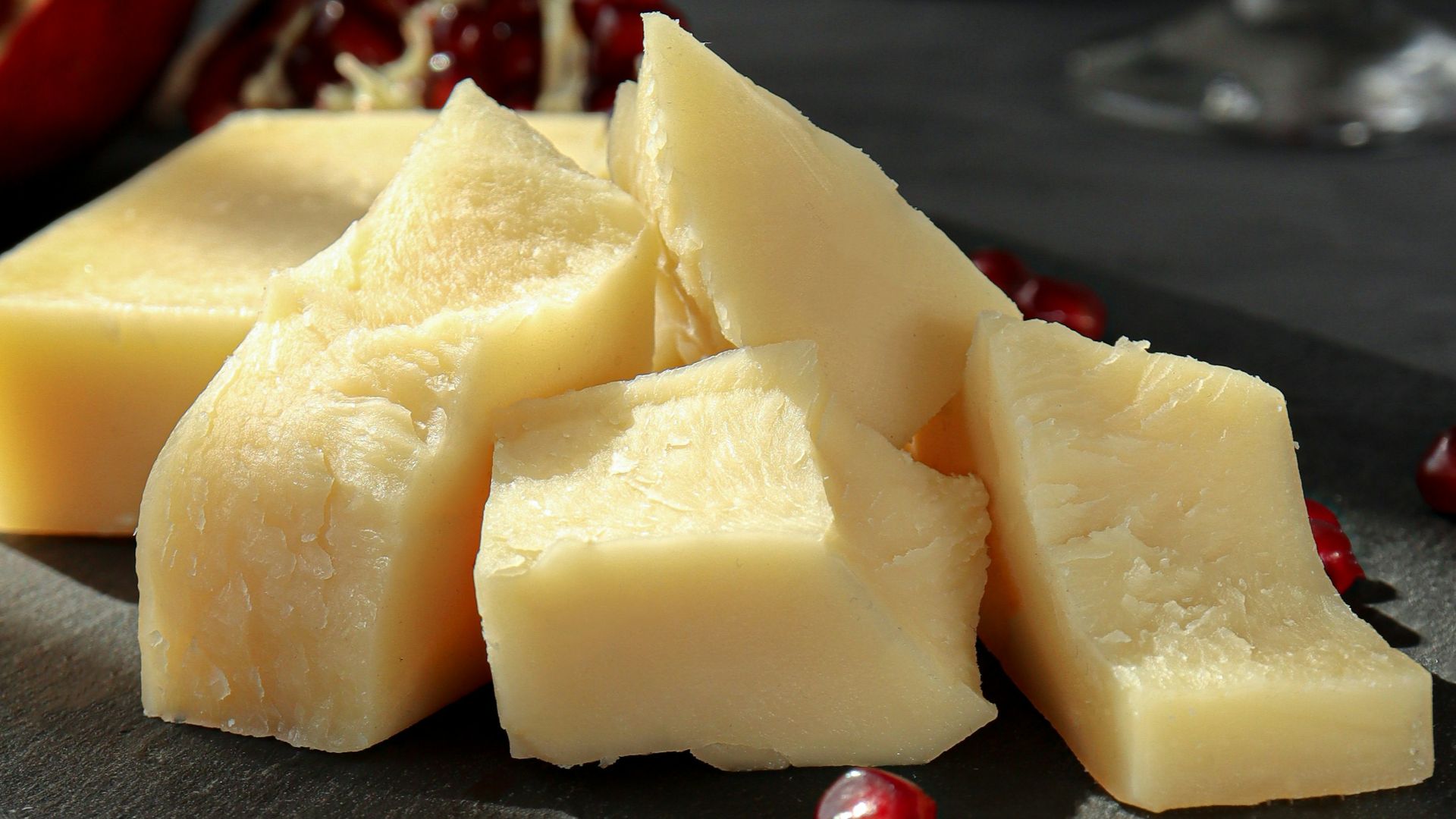 sliced cheese on black plate beside wine glass