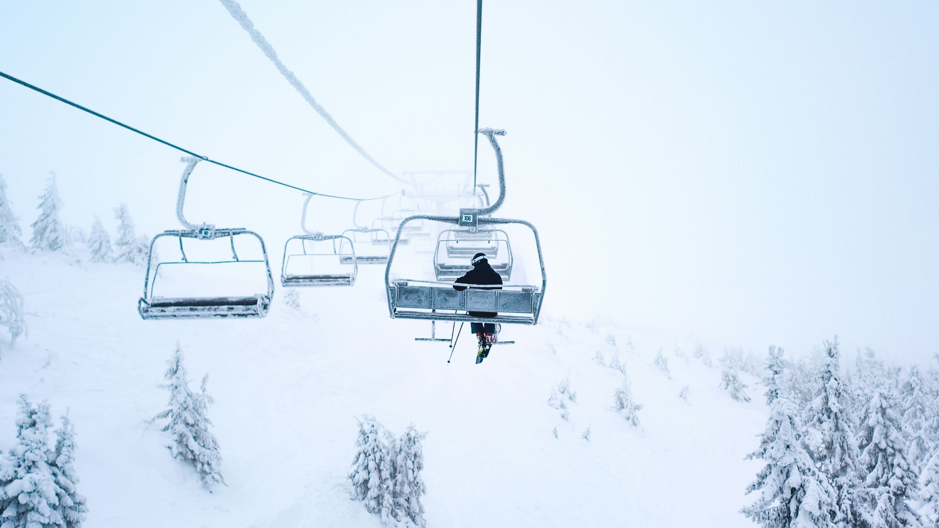 person riding cable train above snow covered field