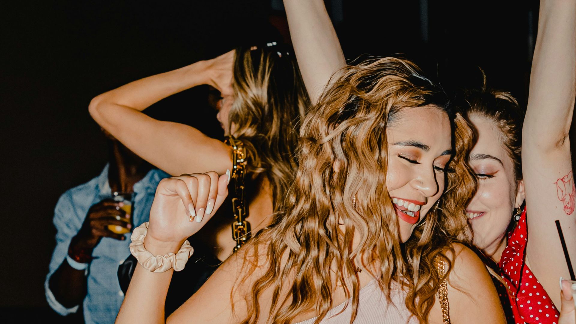 woman in red tank top and blue denim shorts standing beside woman in black tank top