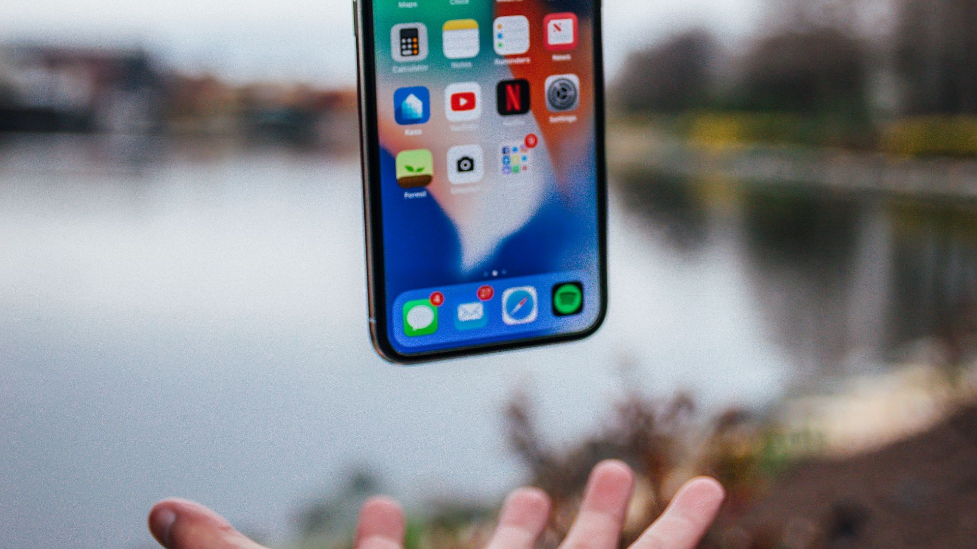 silver iPhone X floating over open palm