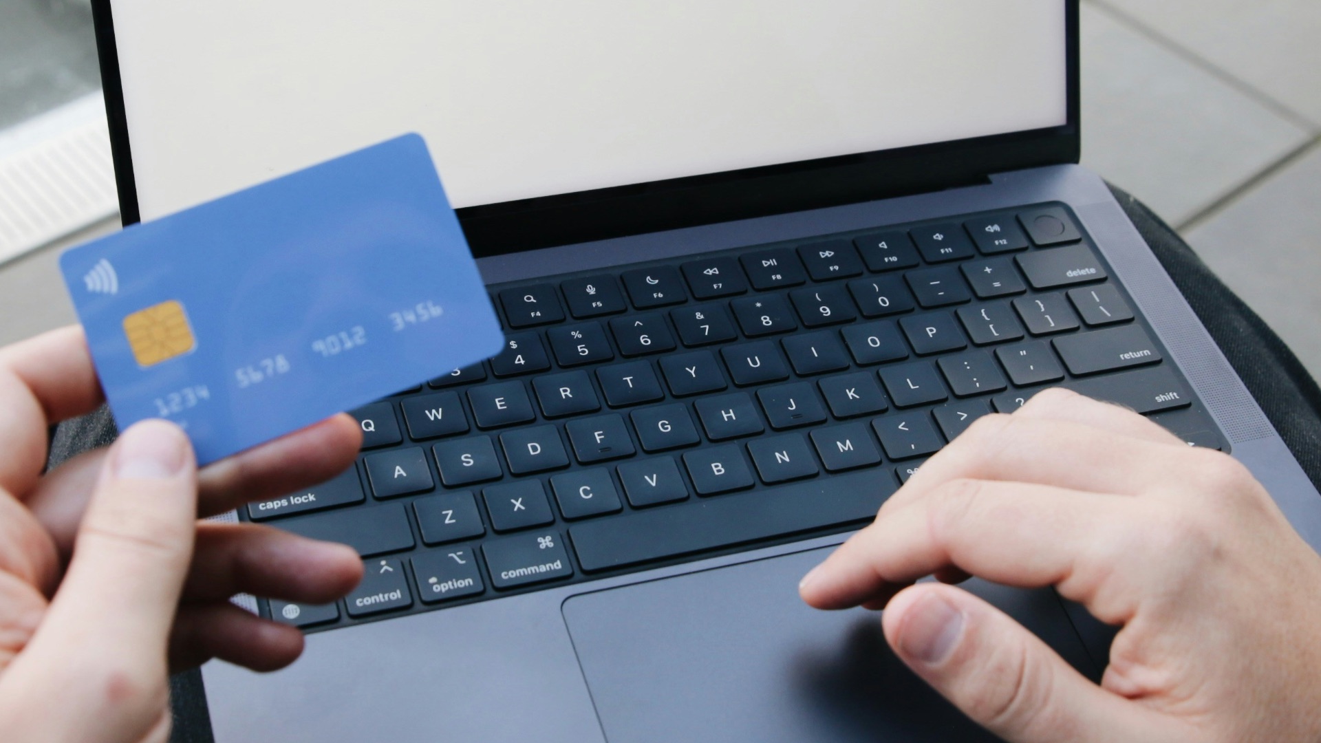 A person sitting in a chair with a laptop and a credit card