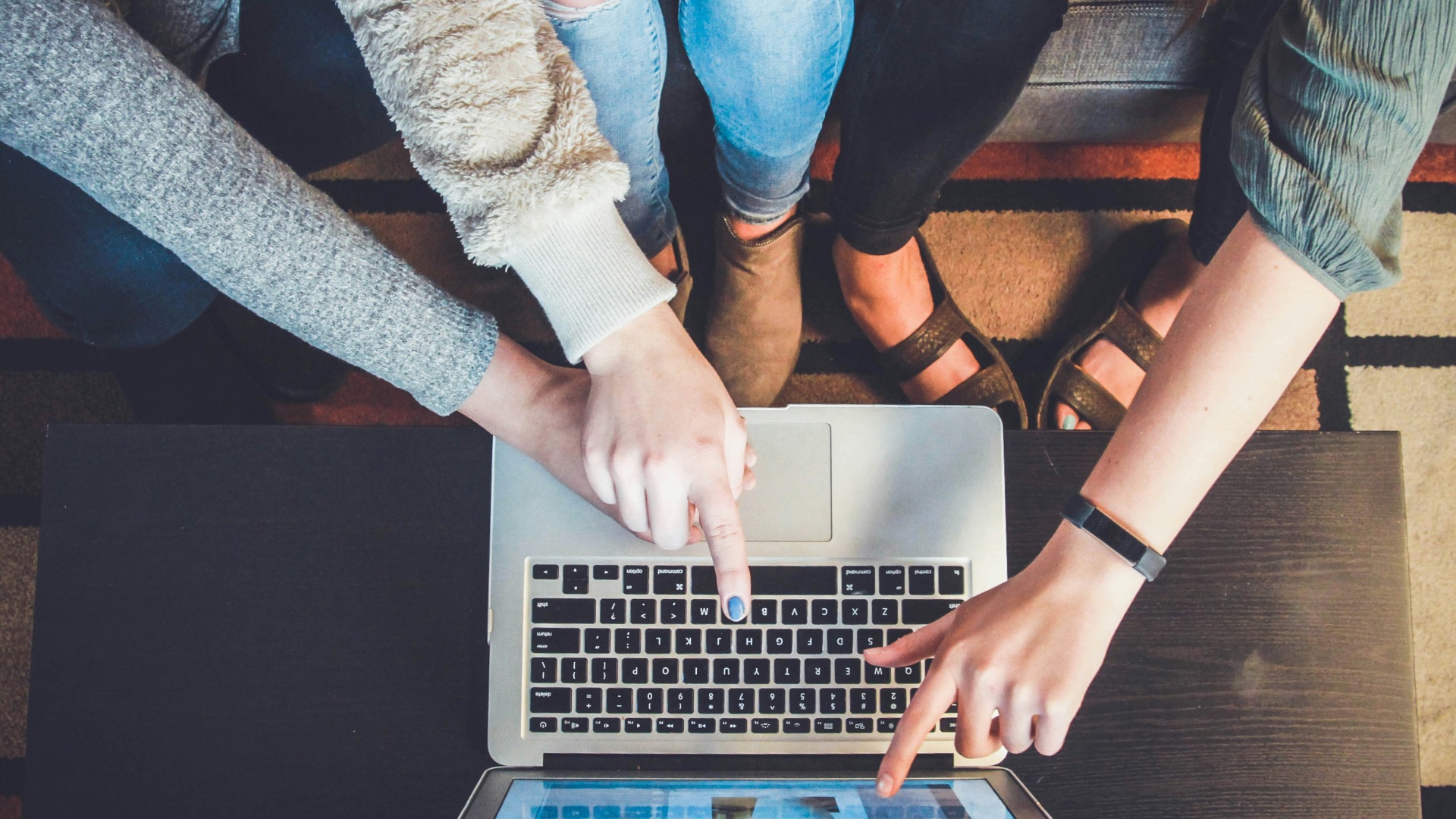three person pointing the silver laptop computer
