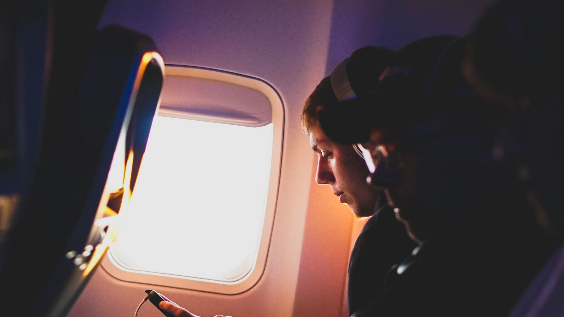 photo of three people listening to music inside airplane