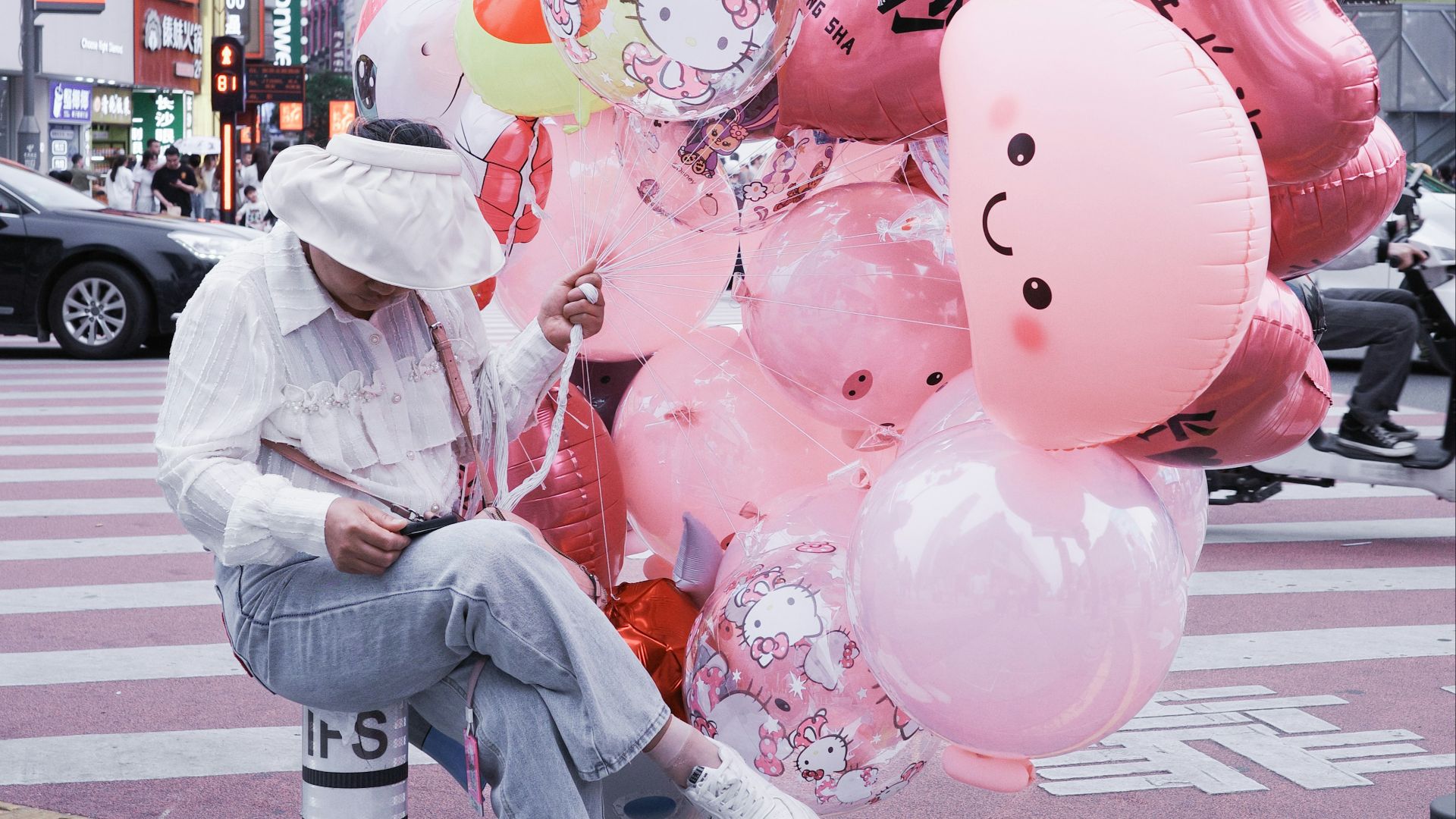 Person with pink balloons on city street
