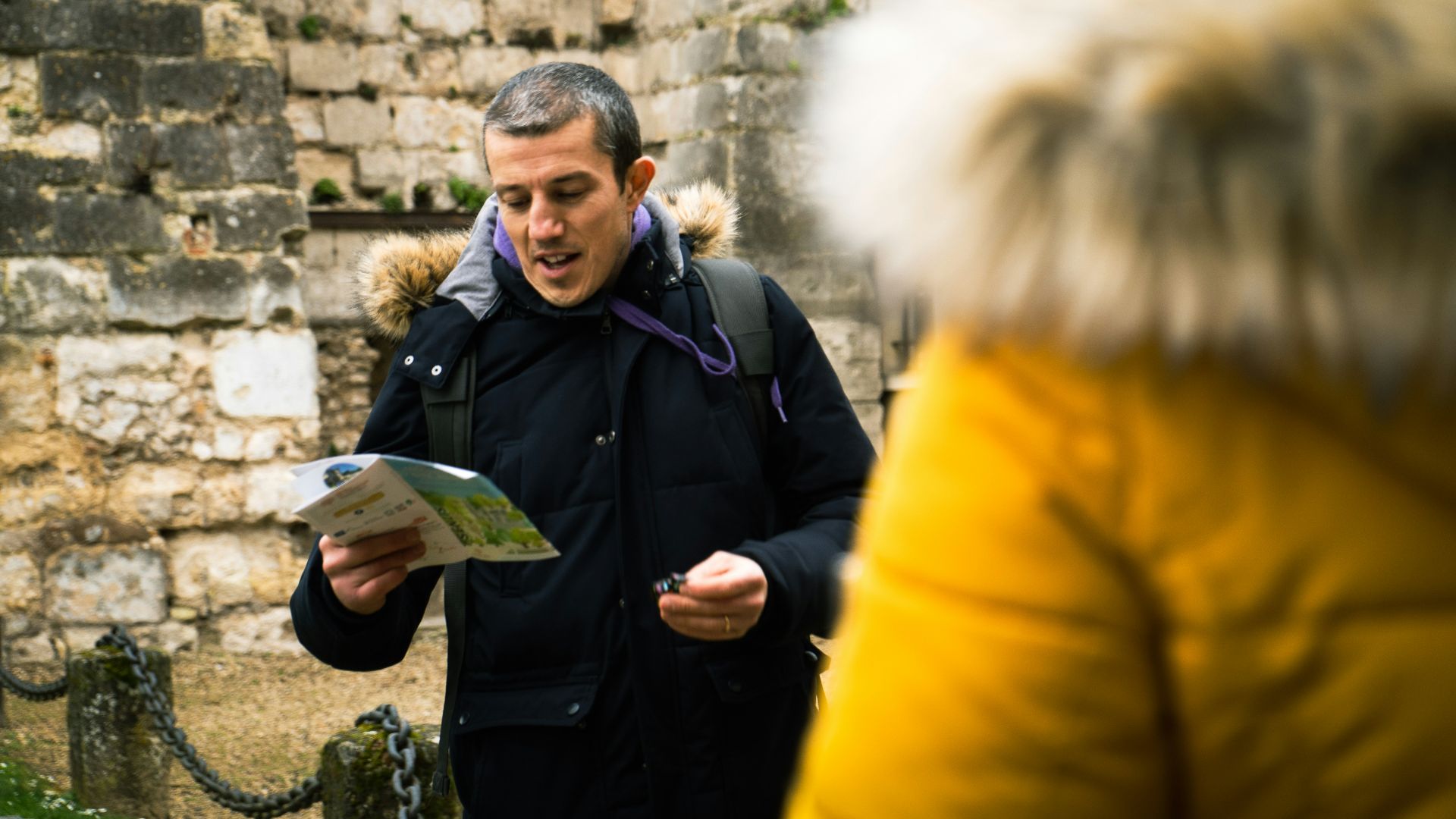a man standing in front of a stone wall