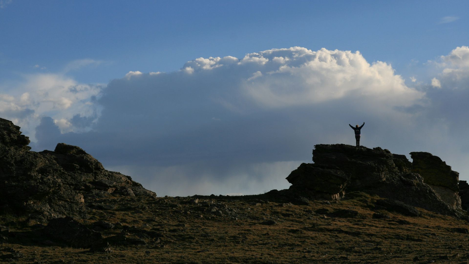 person standing on rock under white clouds