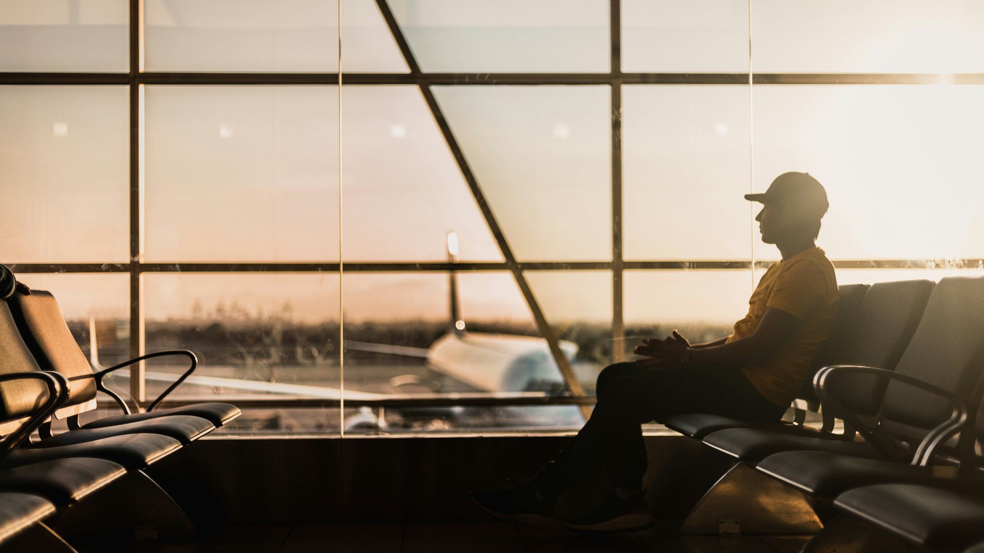 man sitting on gang chair near window