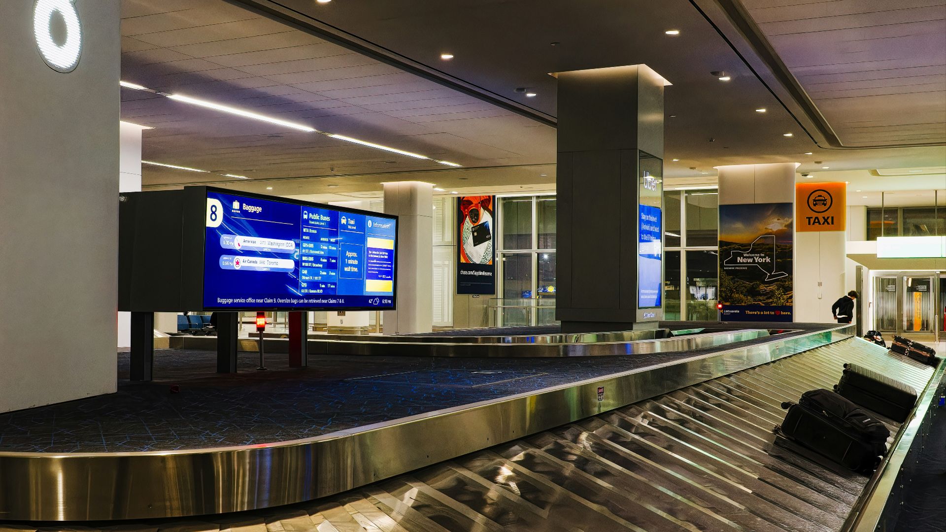a luggage carousel in an airport with a large screen