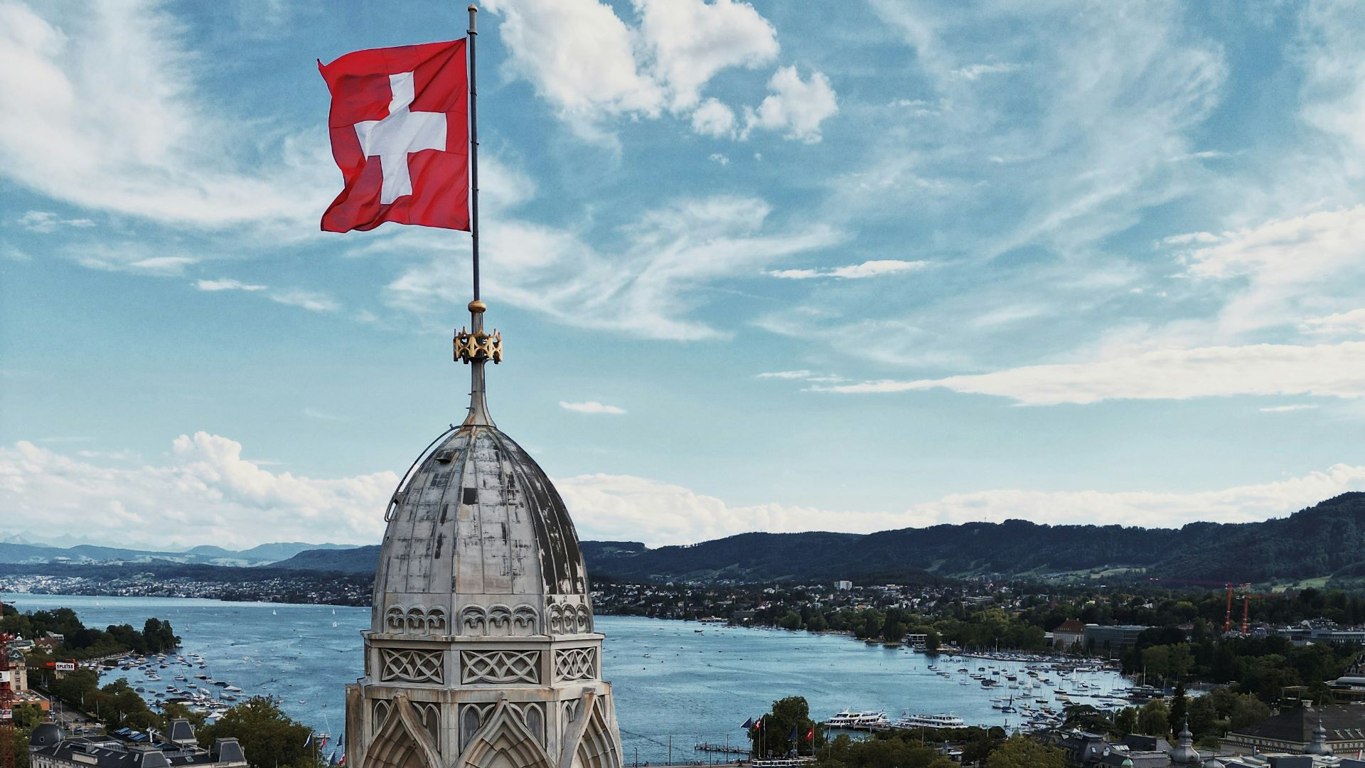a large building with a flag on top and a body of water in the background