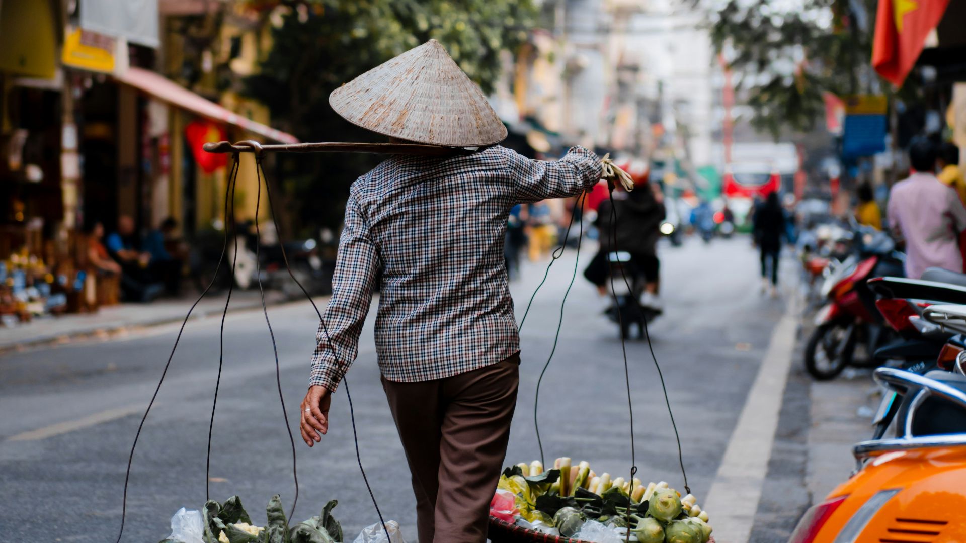 woman in gray coat holding umbrella while walking on street during daytime