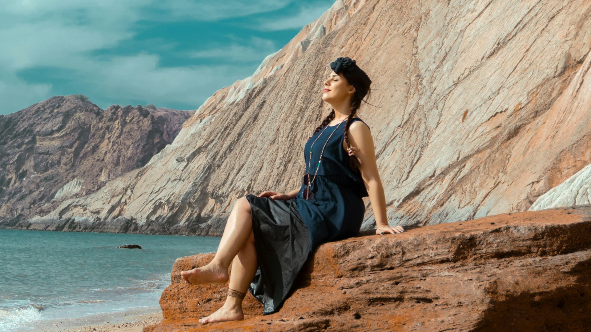 a woman sitting on a rock on the beach