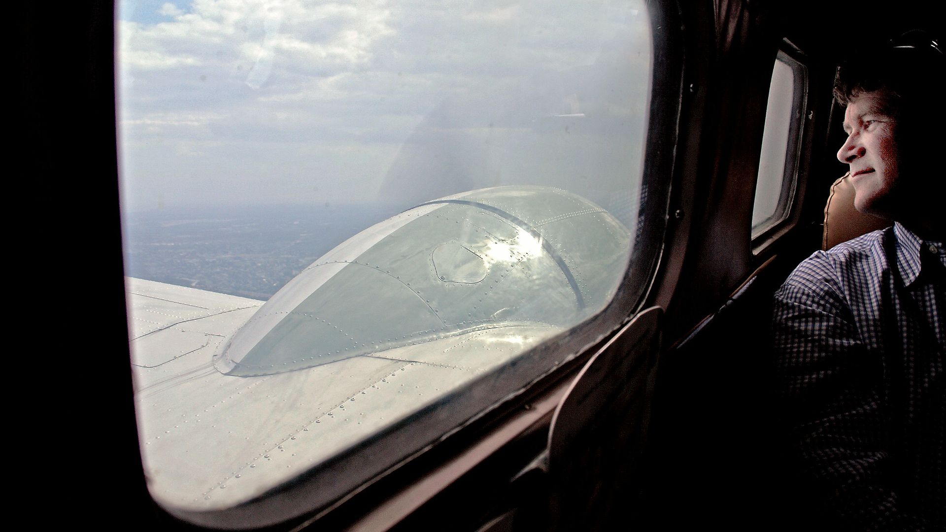 Man looking out airplane window at clouds