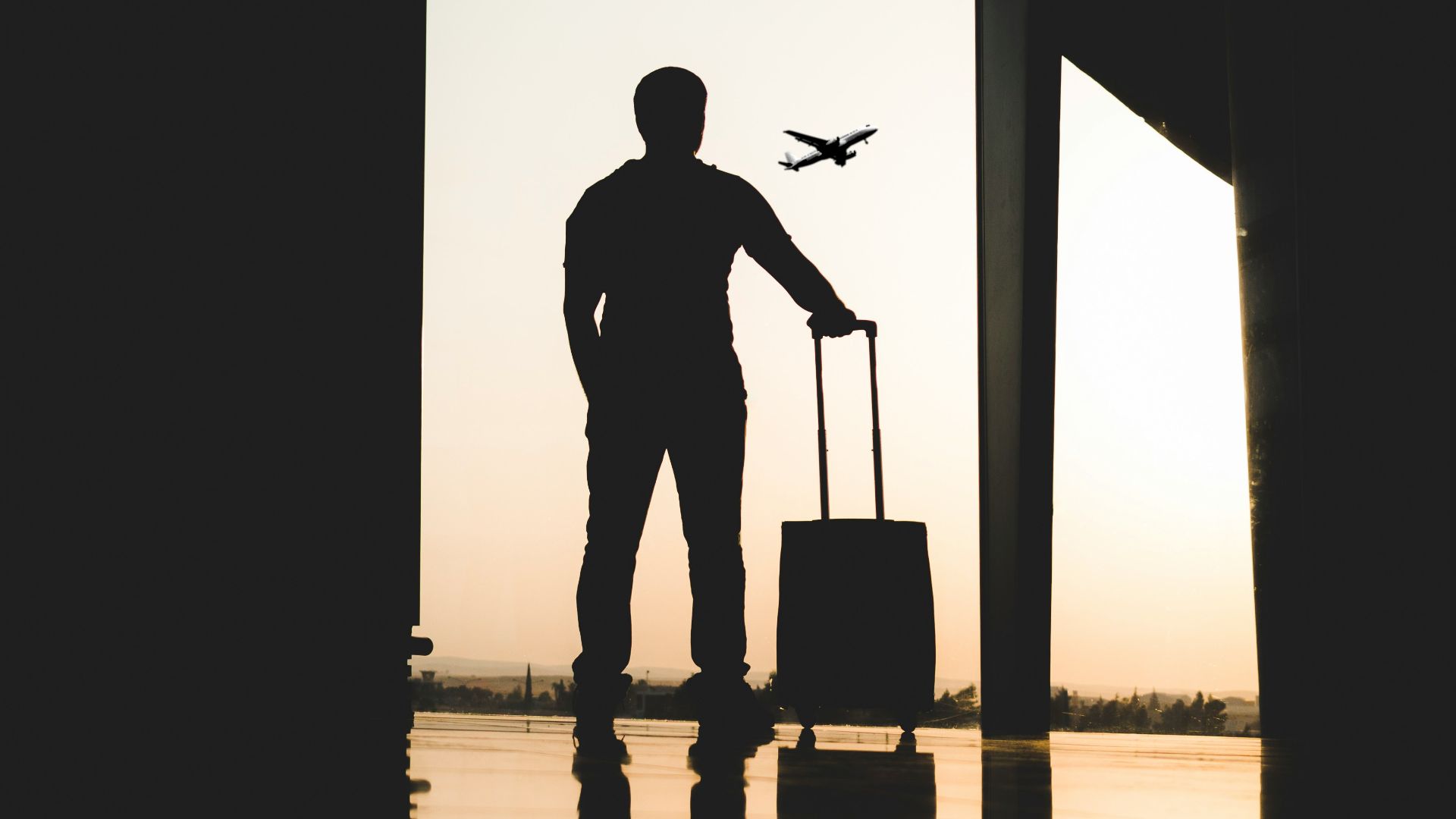 silhouette of man holding luggage inside airport