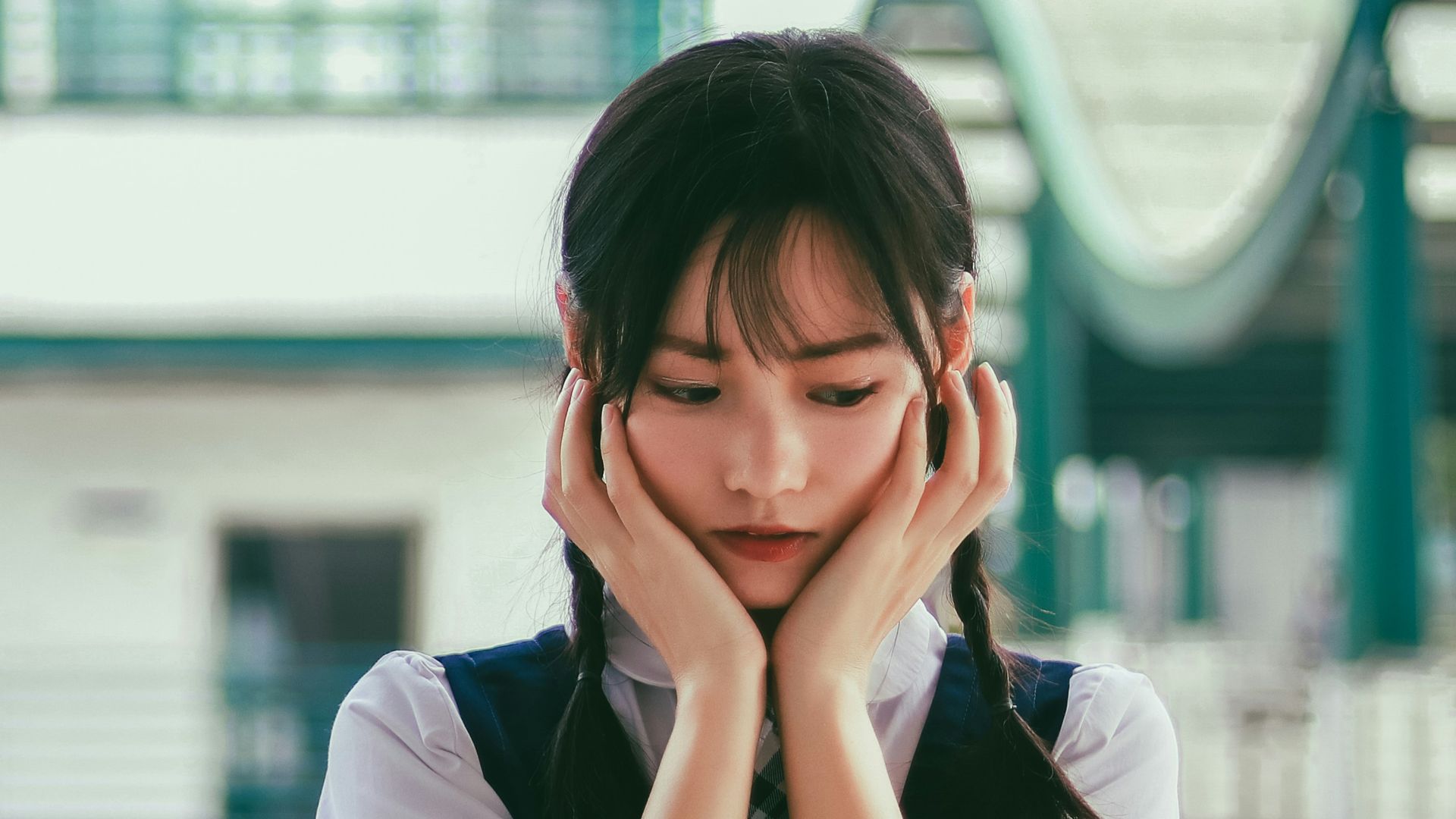 woman holding her face standing near white and green concrete building