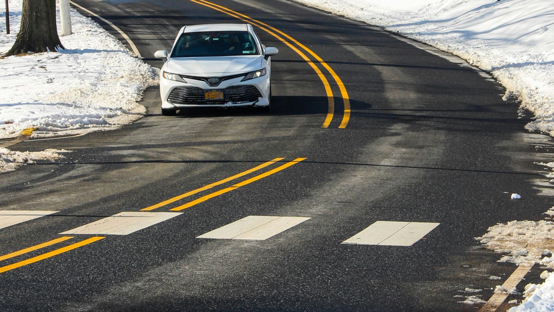 a white car driving down a snow covered road