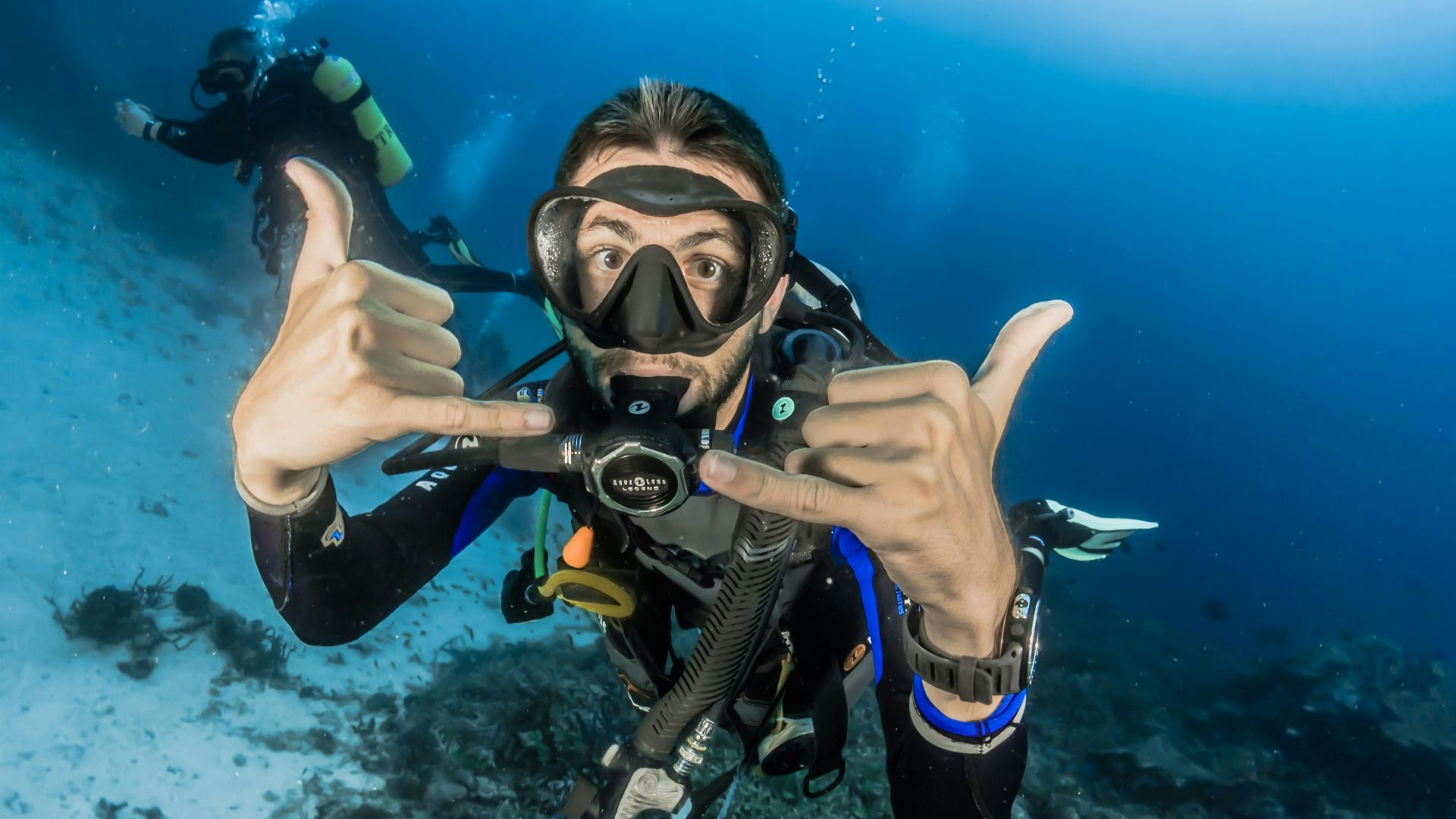 man underwater making hand signs