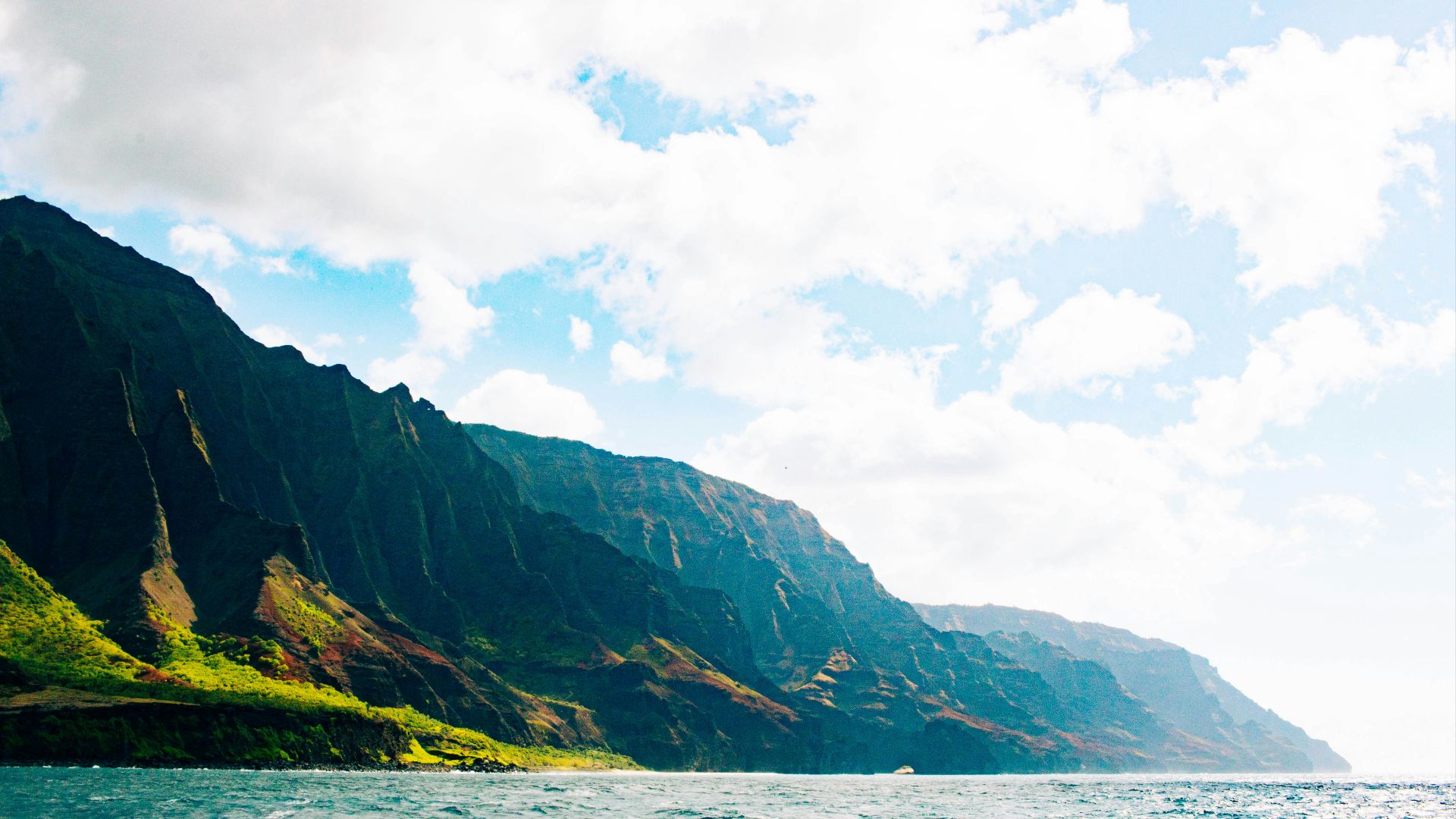green and black mountain beside body of water during daytime