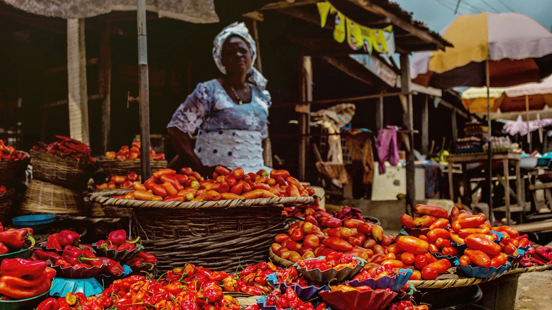 man in white long sleeve shirt and white hat standing in front of fruit stand