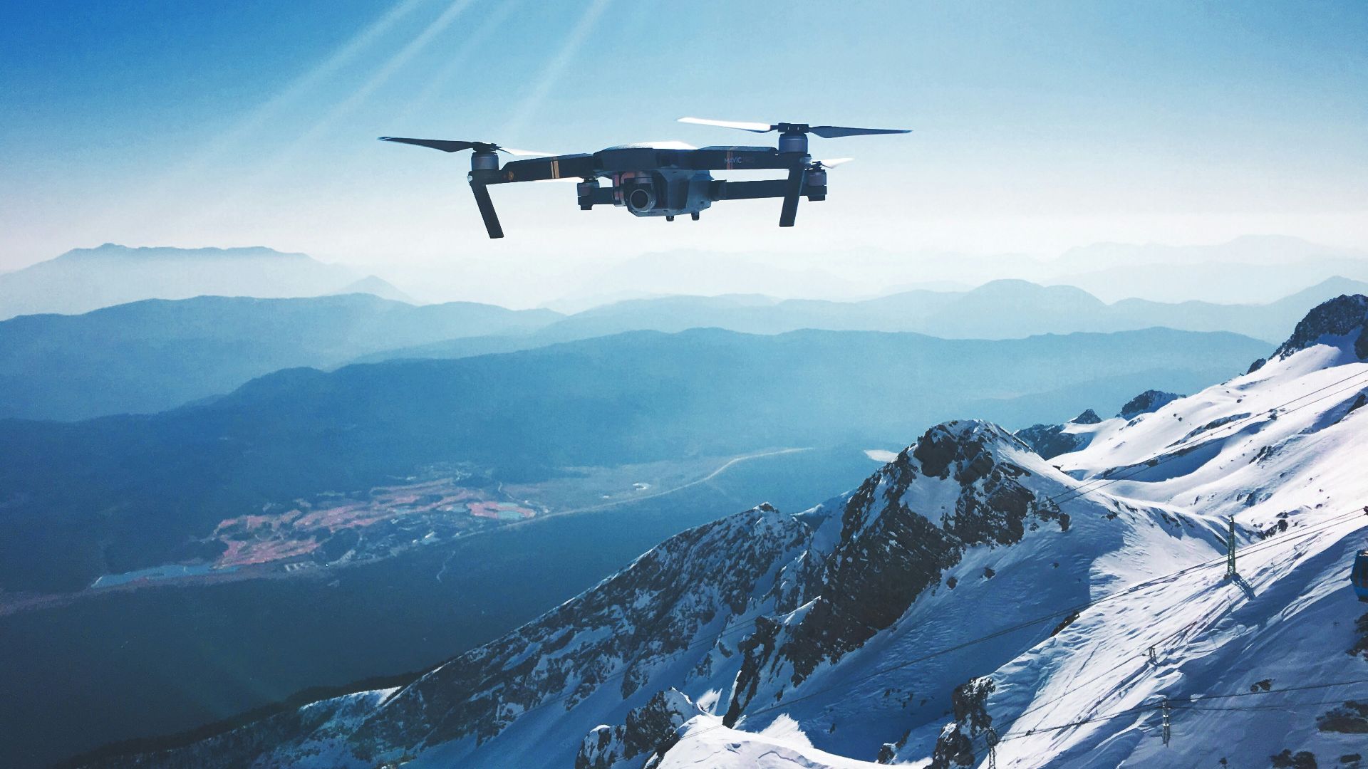 white quadcopter drone flying near snow mountain during daytime