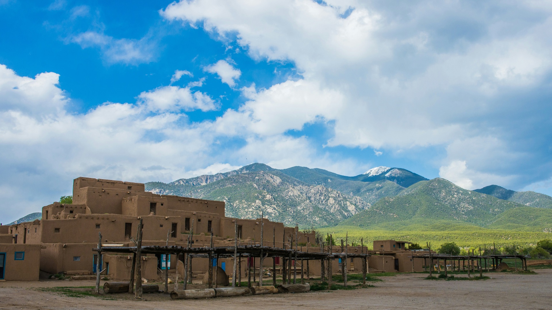a large adobe building with mountains in the background