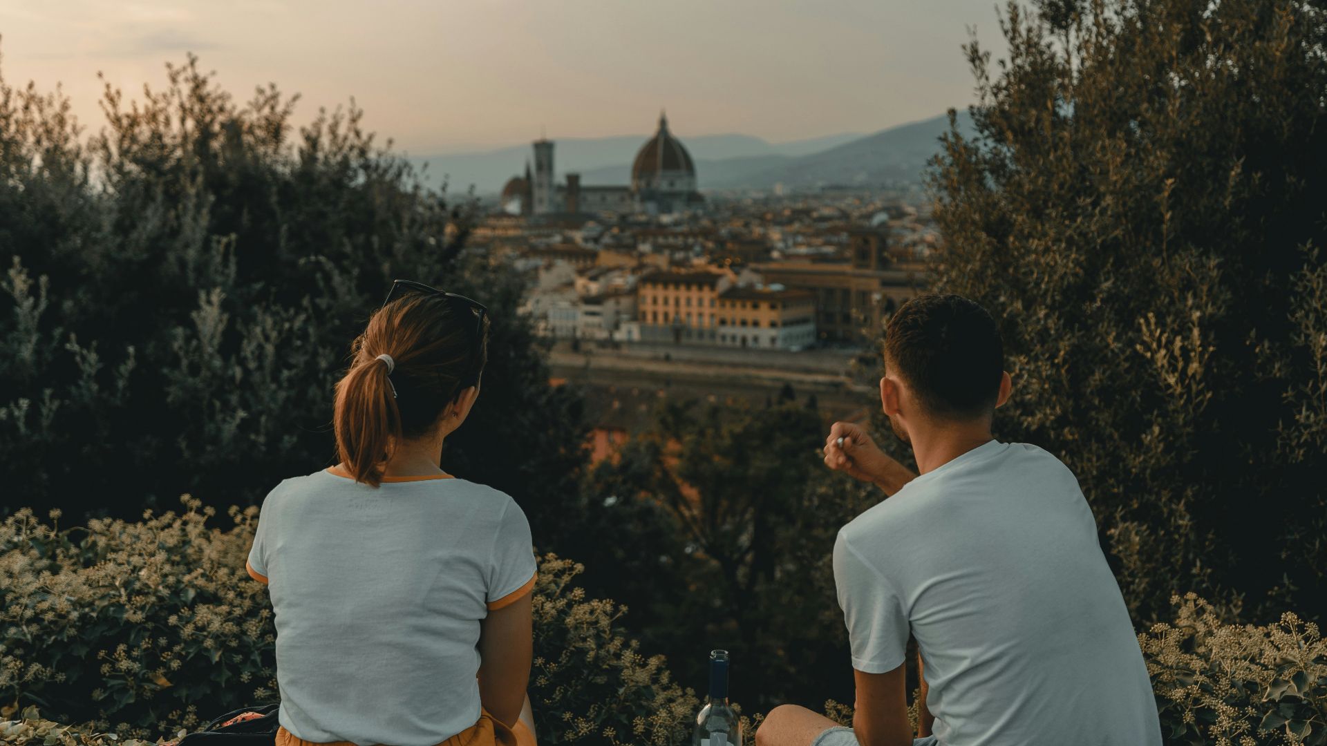 woman and man wearing white shirt while sitting near green trees during daytime